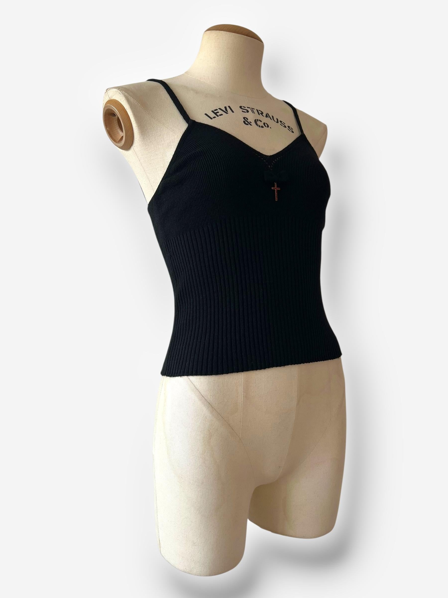 

Ein wunderschönes und seltenes Strickoberteil aus der kultigen 1990er-Ära von Dolce & Gabbana. Dieses schwarze Modell hat feine Spaghettiträger und einen dramatischen Kreuzanhänger in der Mitte, der mit leuchtend roten Steinen verziert ist und
