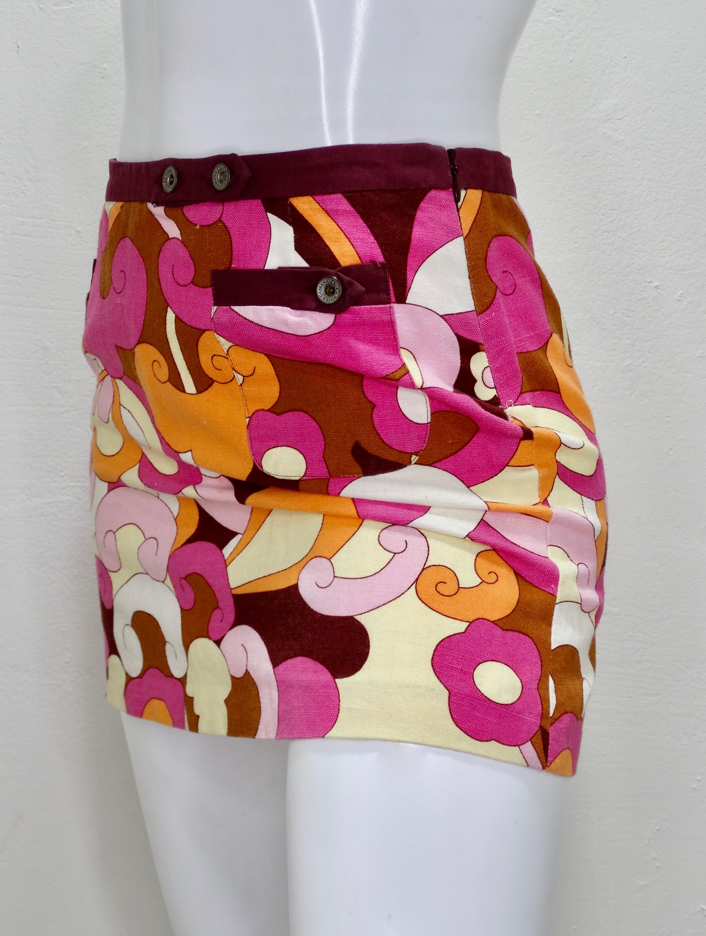 ¡Todos necesitamos una mini en nuestro armario! De los años 90, esta minifalda Dolce & Gabbana presenta un motivo abstracto multicolor inspirado en los años 70, con dos minibolsillos delanteros, un ribete morado y botones a presión en relieve.