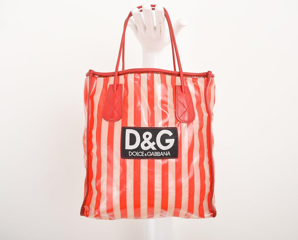 A 1990's red striped and transparent vinyl mini tote bag, by Dolce & Gabbana.
 
Features;
Red leather piping detail
Red leather Sphagetti strap top handles
Iconic D&G exterior logo patch
Large singular interior compartment 
 
Sizing;
Length;