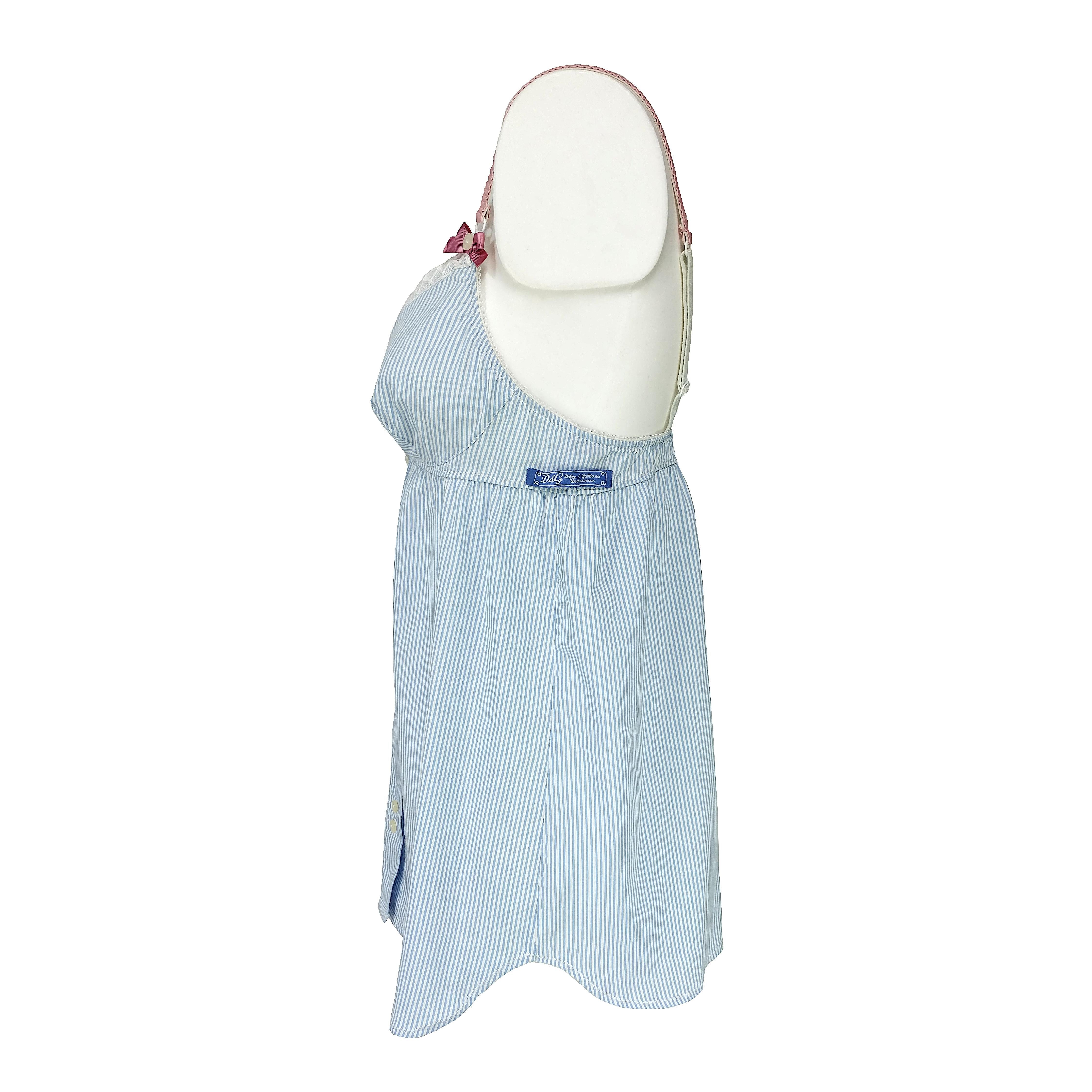 A very special babydoll in a white and azure stripes cotton popeline fabric. It features six bottons on the front side, all engraved with the Dolce & Gabbana logo, a white lace on the neckline, pink shoulder straps and bows. Both the straps and the