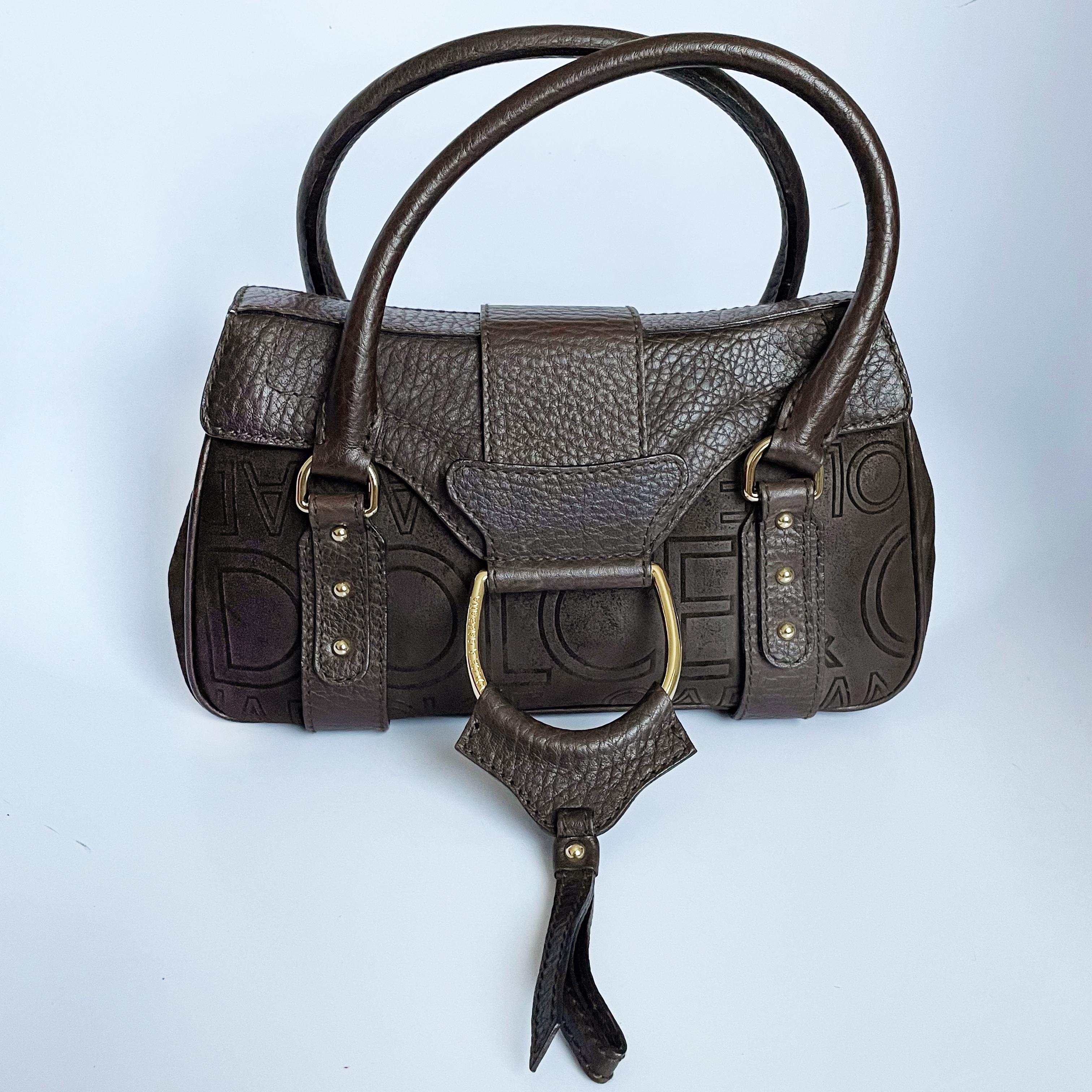 Authentic, preowned Dolce & Gabbana brown D-ring flap bag, likely from the 2000s. 

Made from sueded leather with pebbled leather trim, it features abstract Dolce & Gabbana logos throughout. Fastens with hidden magnet under flap and lined in logo