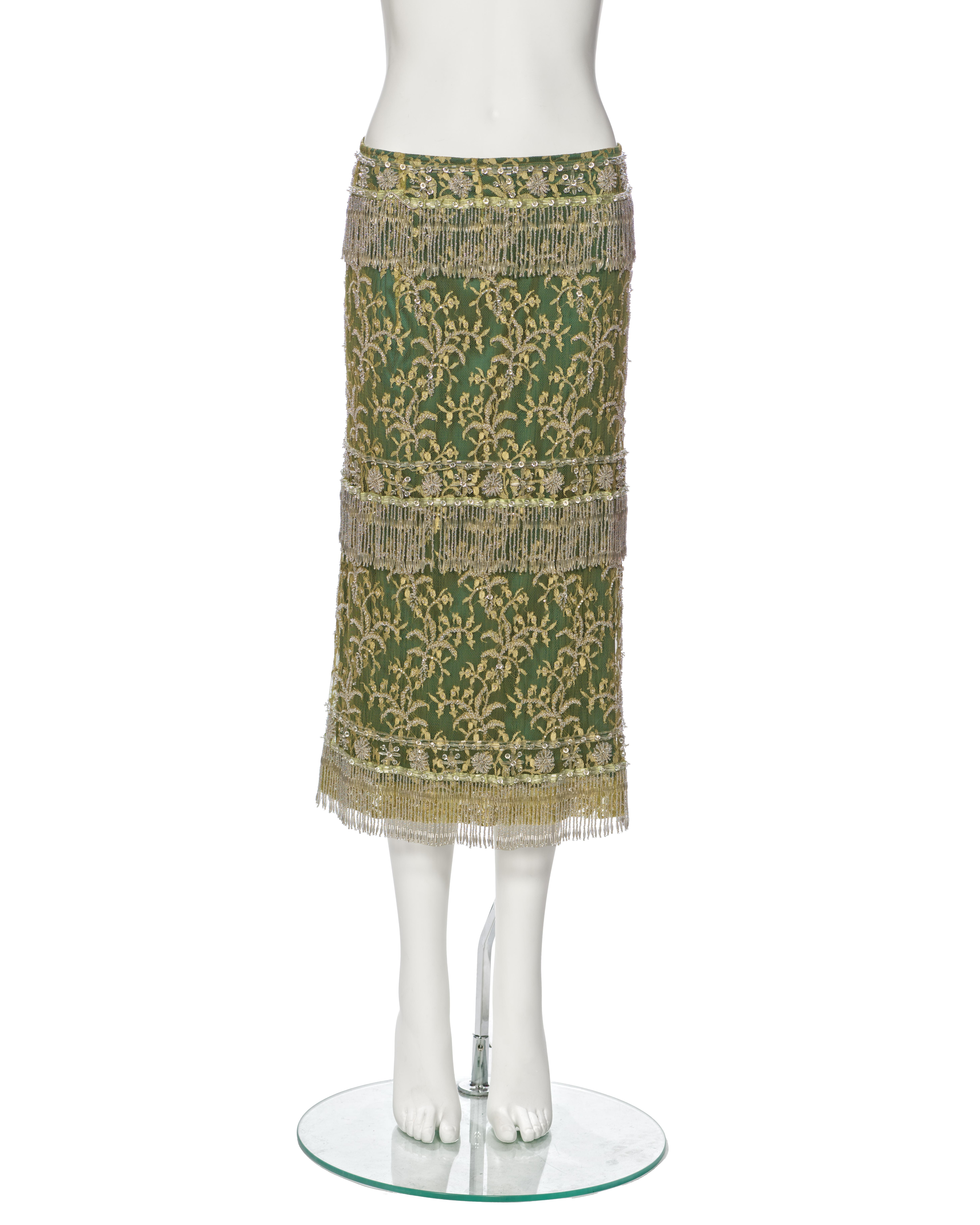 ▪ Rare Dolce & Gabbana Beaded Lace Evening Skirt
▪ Spring-Summer 2000
▪ Expertly crafted from chartreuse lace, meticulously embellished with clear beads
▪ Adorned with tiered clear beaded tassel trim
▪ Lined with luxurious green silk
▪ Cut to an