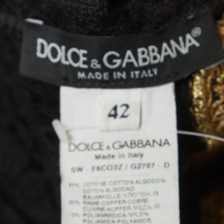 Cette magnifique robe de Dolce & Gabbana promet que vous ne passerez jamais inaperçue lorsque vous l'enfilerez ! Cette création noire intemporelle est fabriquée à partir de tissus de qualité et comporte une garniture dorée qui rehausse l'attrait de