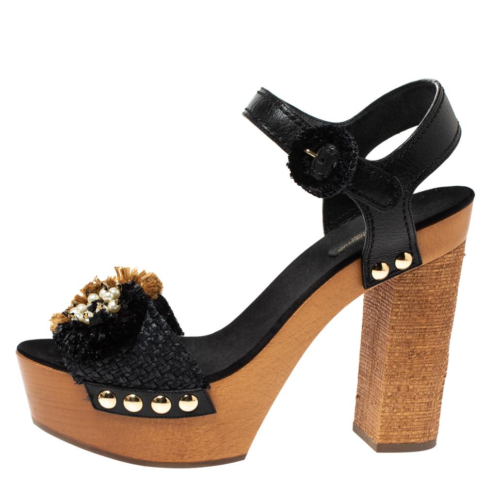 Flaunt your love for fashion and luxury with these stunning sandals by Dolce & Gabbana. Crafted in Italy, they are made from black leather and brown raffia. They are styled with open toes, vamps detailed with embellishments, buckled ankle straps,