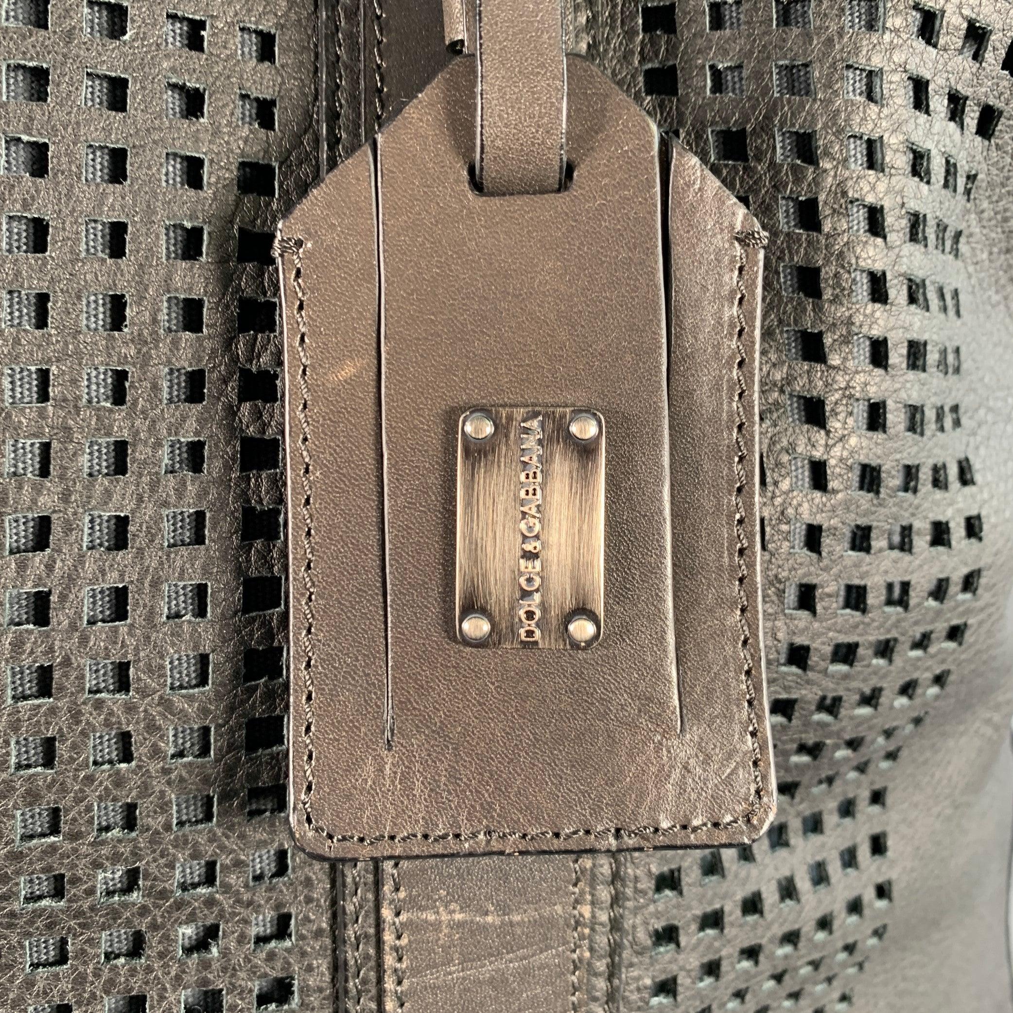 Sac de nuit DOLCE & GABBANA
en cuir noir et garnitures en cuir marron, avec un motif de grille perforée, des poignées supérieures avec sangles de sac à dos et une fermeture à glissière. Fabriqué en Italie. Très bon état. Signes d'usure modérés sur