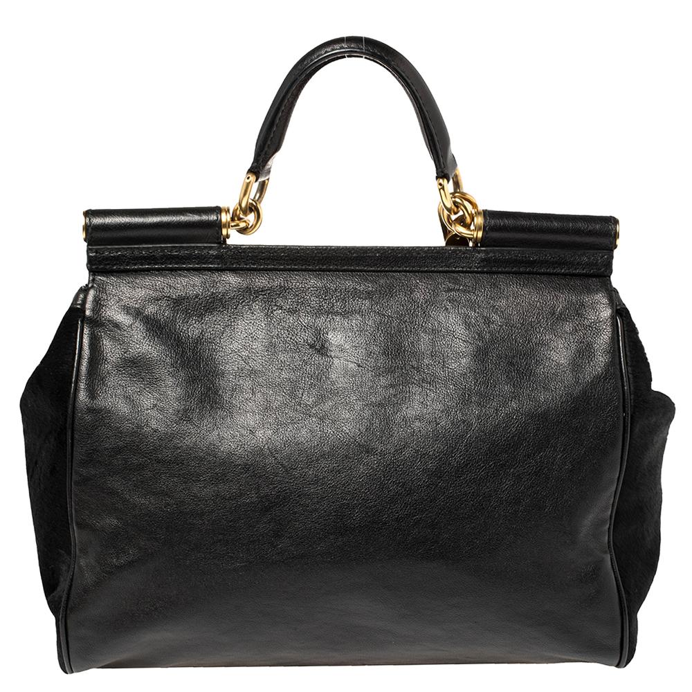 The iconic Miss Sicily bag by Dolce & Gabbana is named after Domenico Dolce's native land and exhibits the aesthetic of Italian glamour. The neat silhouette is made from calfhair and leather in a black shade and features a front flap accented with