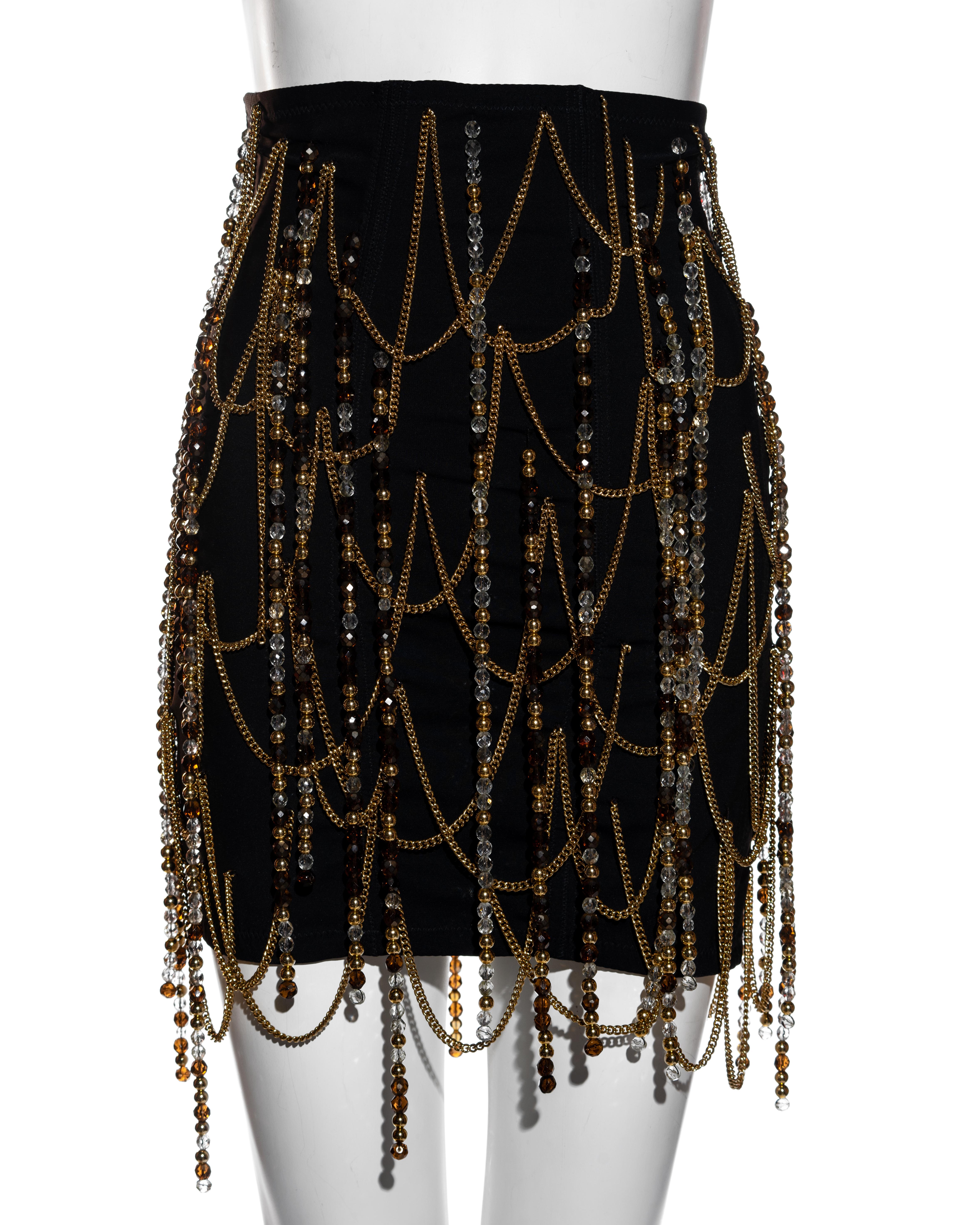 ▪ Dolce & Gabbana Schwarzer Minirock mit Korsett 
▪ Goldfarbene Metallkette als Detail 
▪ Perlenquasten 
▪ Metallhakenverschlüsse in der hinteren Mitte 
▪ IT 42 - FR 38 - UK 10 - US 6
▪ Frühjahr-Sommer 1991