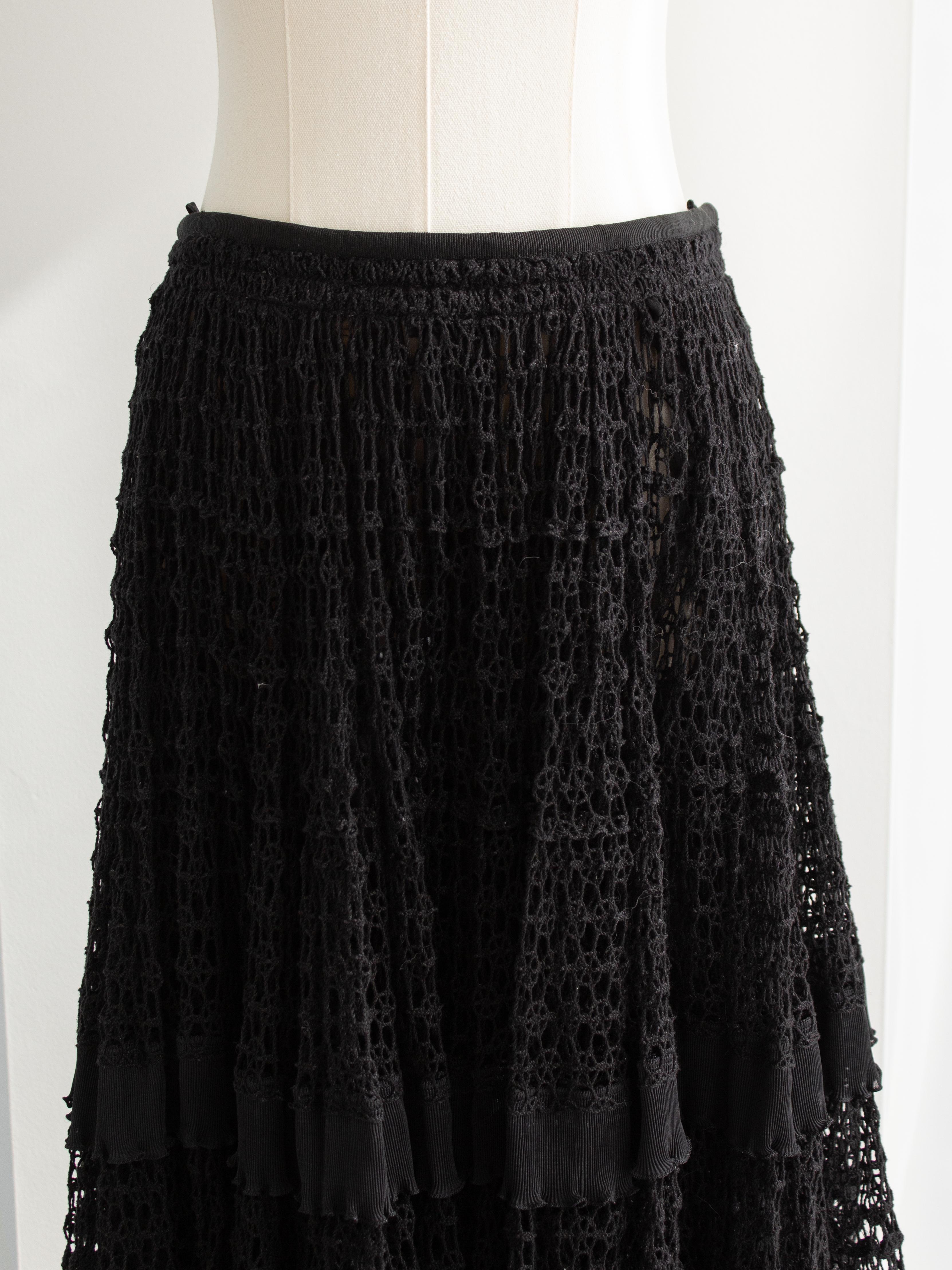 This elegant and timeless Dolce & Gabbana black midi skirt features a delicate lace design with intricate detailing. The skirt is tiered with multiple layers, creating a soft and voluminous silhouette, perfect for adding a touch of sophistication to