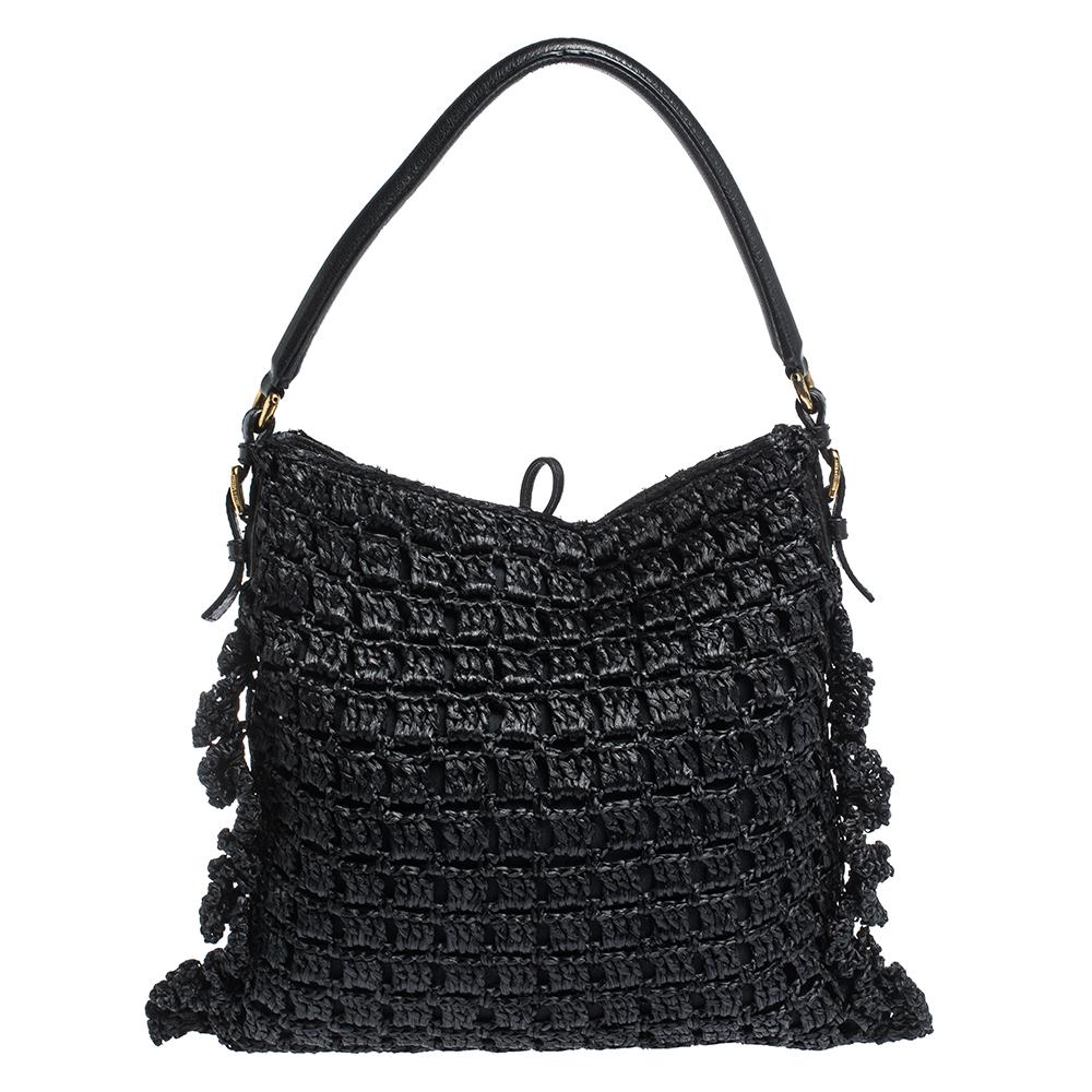 This stunning hobo by Dolce & Gabbana is a must-have. It is crafted in Italy and made of quality straw. It comes in a stunning shade of black and adds a touch of style to every outfit. The exterior features leather trims and signature brand logo