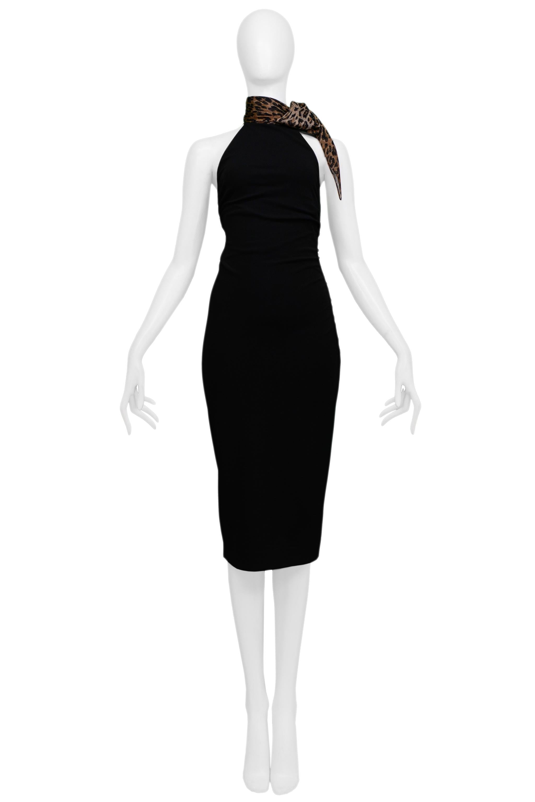 Resurrection Vintage a le plaisir de vous proposer une robe vintage Dolce & Gabbana en viscose noire avec une écharpe léopard attachée, avec un corps ajusté, un corsage coupé en diagonale, des épaules apparentes et une longueur juste en dessous du
