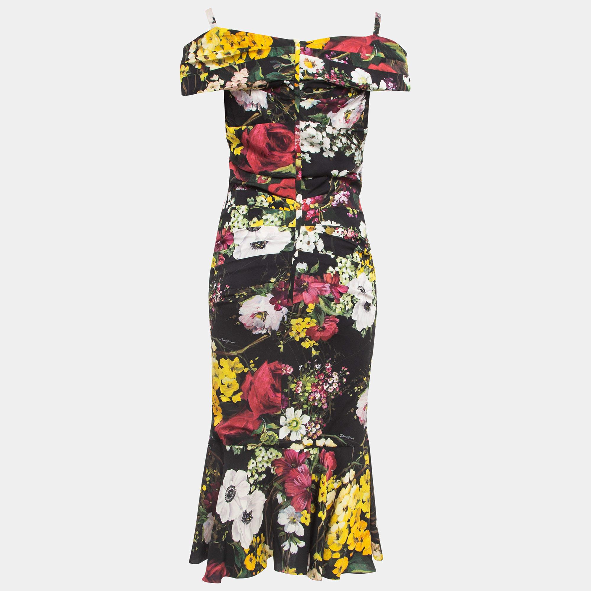 Dieses wunderschöne Kleid mit Blumenmuster von Dolce & Gabbana wird Sie direkt in die warmen Erinnerungen des Sommers versetzen! Die schwarze Silhouette ist mit seitlichen Rüschen versehen und zeigt sich mit kalten Schulterärmeln und einem