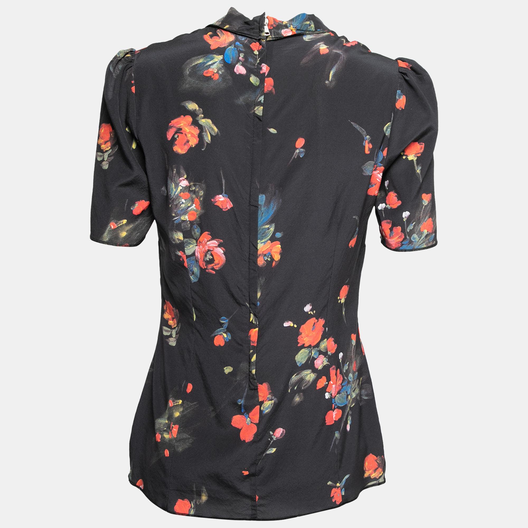 This beautiful blouse from Dolce & Gabbana is all about elegance and poise! It is stitched using black silk fabric, with multicolored floral prints augmenting its beauty. It showcases a neck-tie, short sleeves, and a zipper at the back. Match this