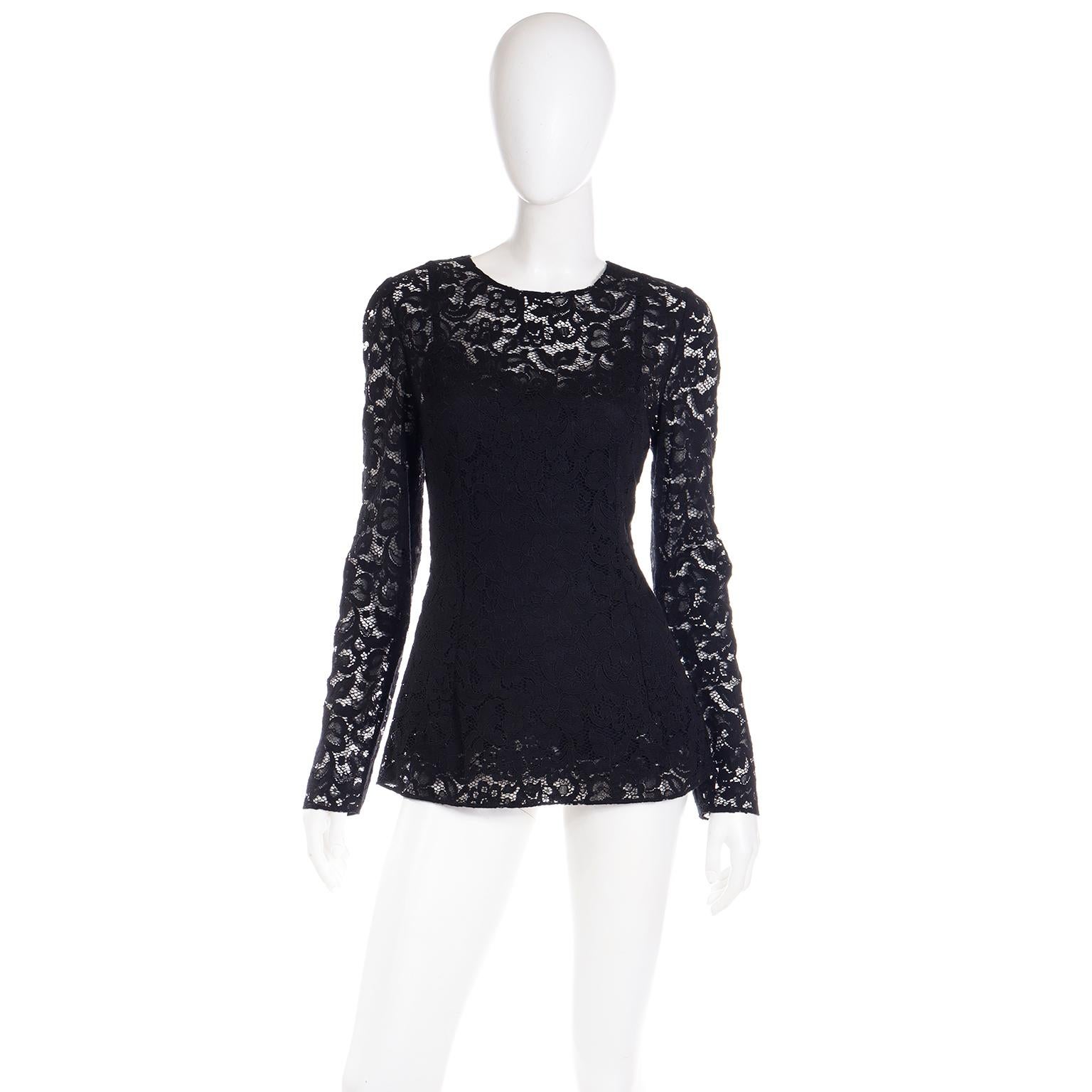 This stunning Dolce & Gabbana sheer black lace long sleeve top has an attached black camisole underneath. The camisole and outer lace portion both have a back center zipper closure. There are princess seams in both the front and back and the top has