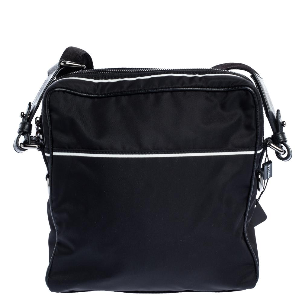 Refined look and durable construction define this smart Dolce & Gabbana messenger bag that is your ideal pick this season. This black messenger bag is crafted from nylon & leather. It is styled with zip pockets, logo detailing in the front and a
