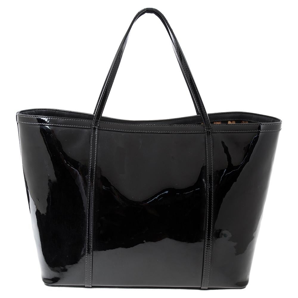 Explore new areas in fashion trends with a classy piece like the Miss Escape tote from the House of Dolce & Gabbana. Glossy black patent leather and gold-toned accents are used to craft this tote. The large spaced interior flaunts an animal print