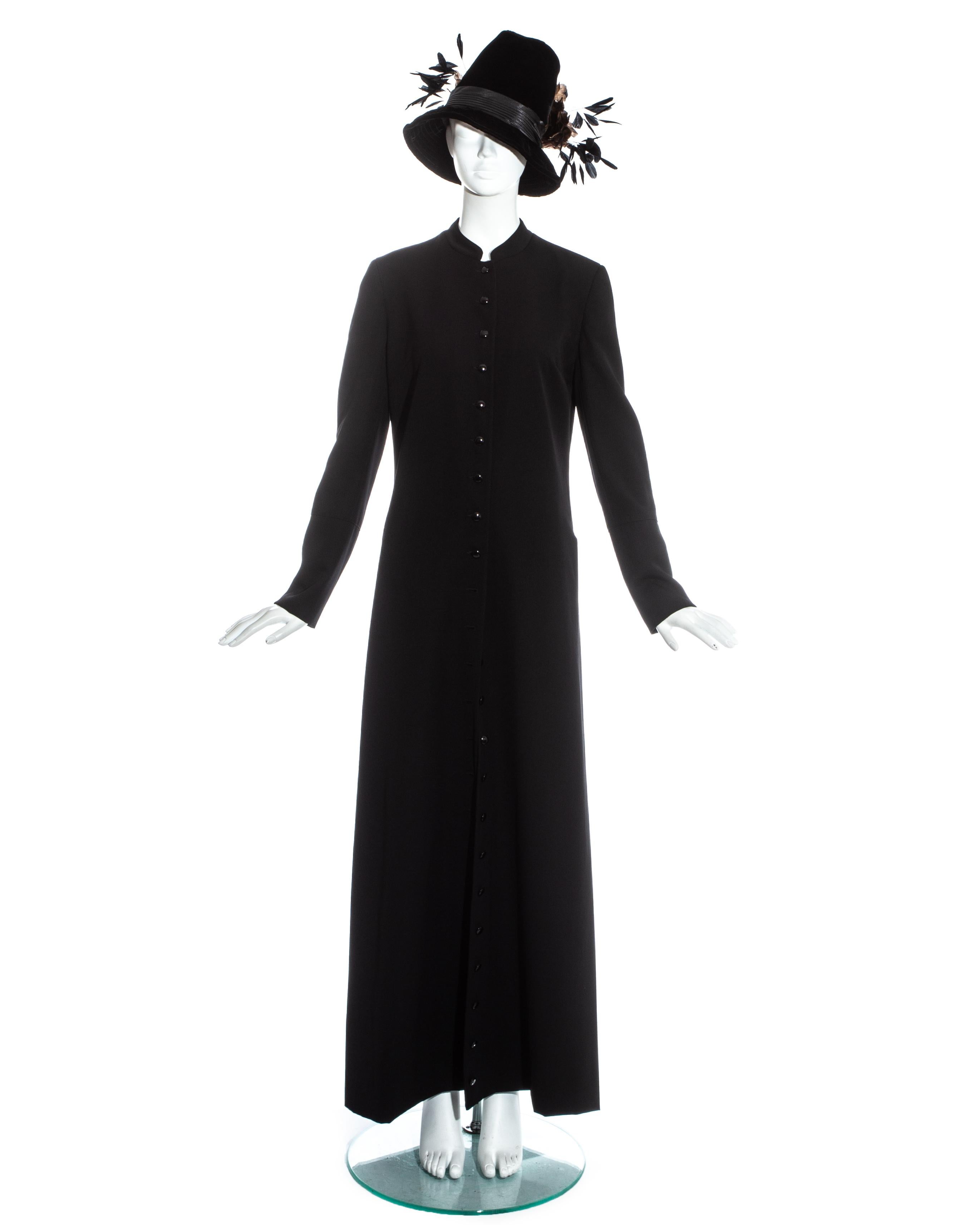 Dolce & Gabbana black full length priest coat with button fastenings from collar to hem. Velvet fedora hat with pleated silk band and feathered motif. 

Fall-Winter 1997