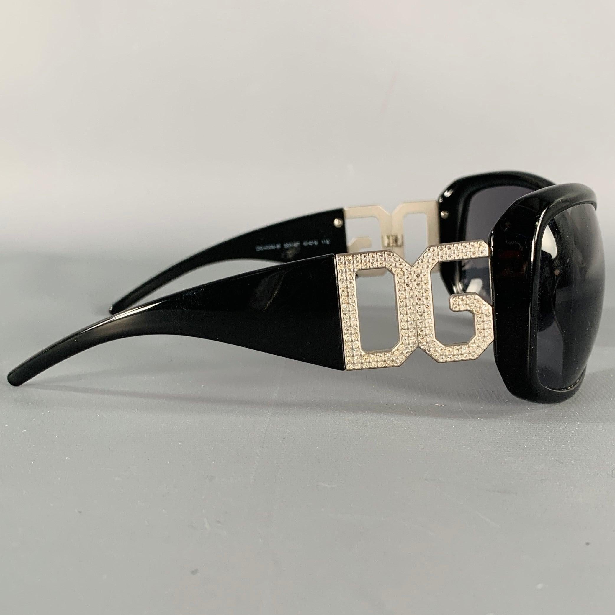DOLCE & GABBANA sunglasses
in a black acetate featuring silver tone metal rhinestone studded DG logo temple arm details. Comes with matching case and box.Excellent Pre-Owned Condition. 

Marked:   DG 4005-B 501/87 61 19 115 

Measurements: 
  Frame