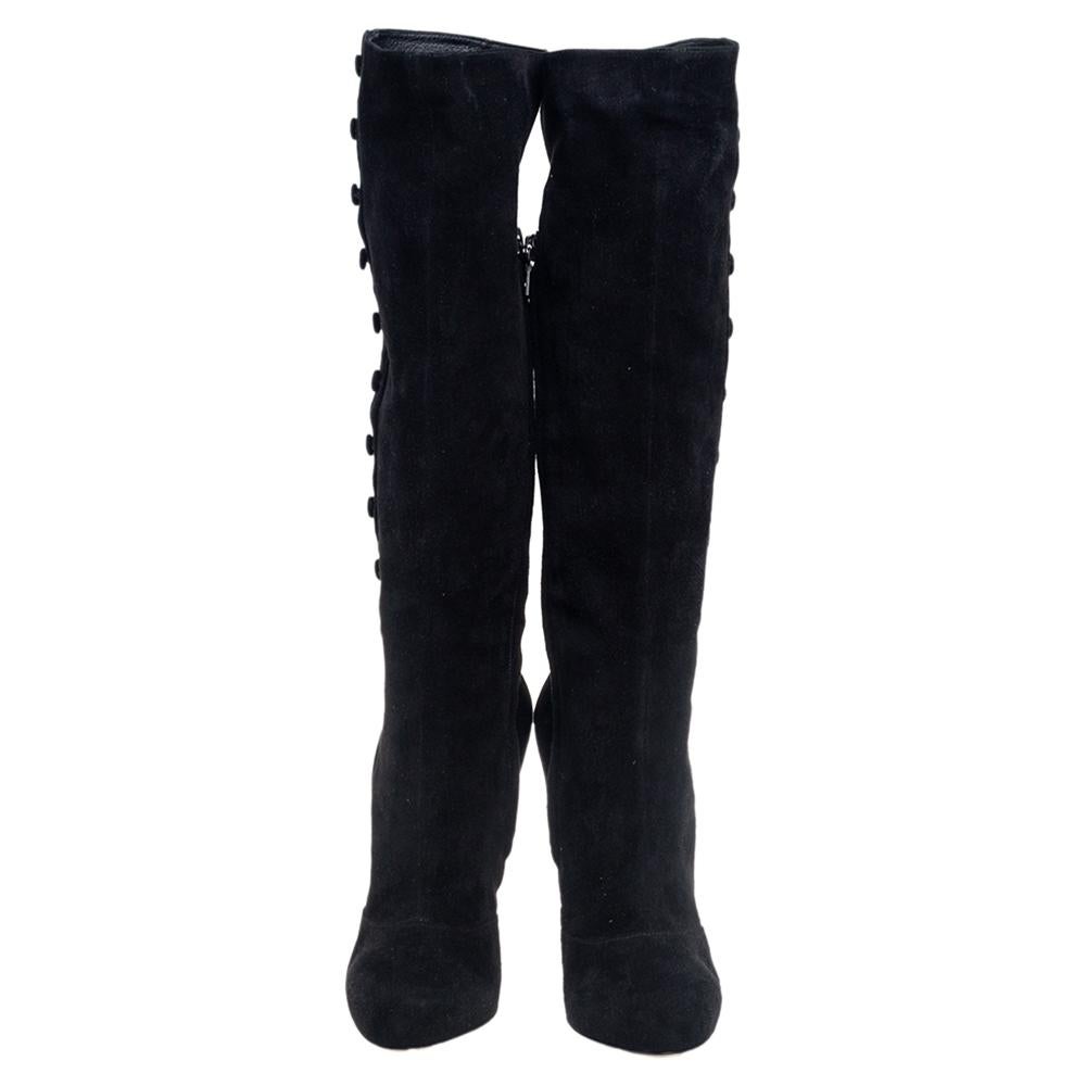This luxe pair of knee-length boots are designed by Dolce & Gabbana from quality black suede. They feature round toes, 10 cm heels, and button detailing on the sides. Pair them up with oversized mini dresses or with denim.

Includes: Price Tag,