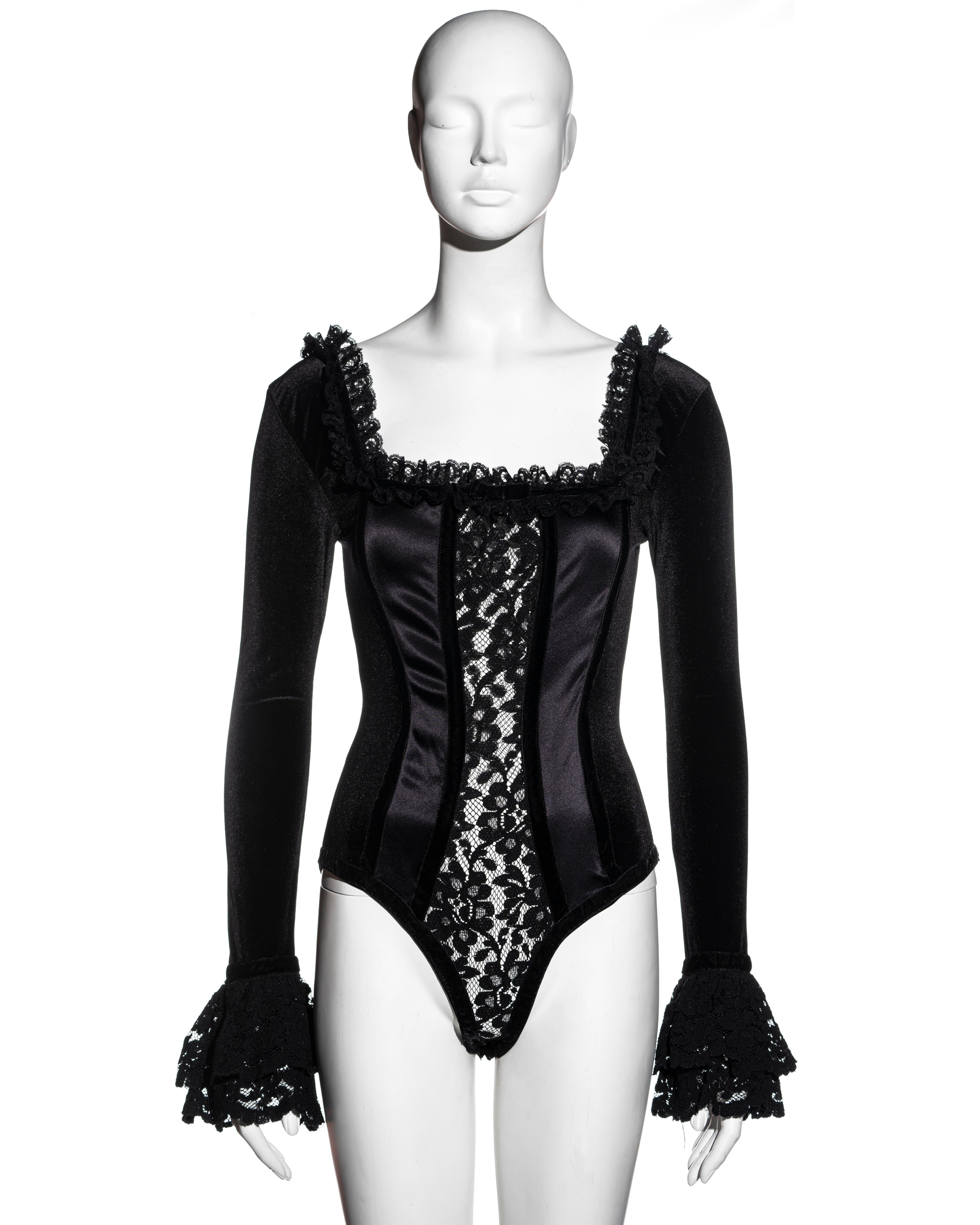 ▪ Dolce & Gabbana black corseted bodysuit
▪ Skin baring lace panel at the center front 
▪ Lace ruffled trim around neckline and cuffs 
▪ Boned bodice 
▪ Nylon spandex blend appears like velvet 
▪ Size Medium 
▪ Spring-Summer 1992