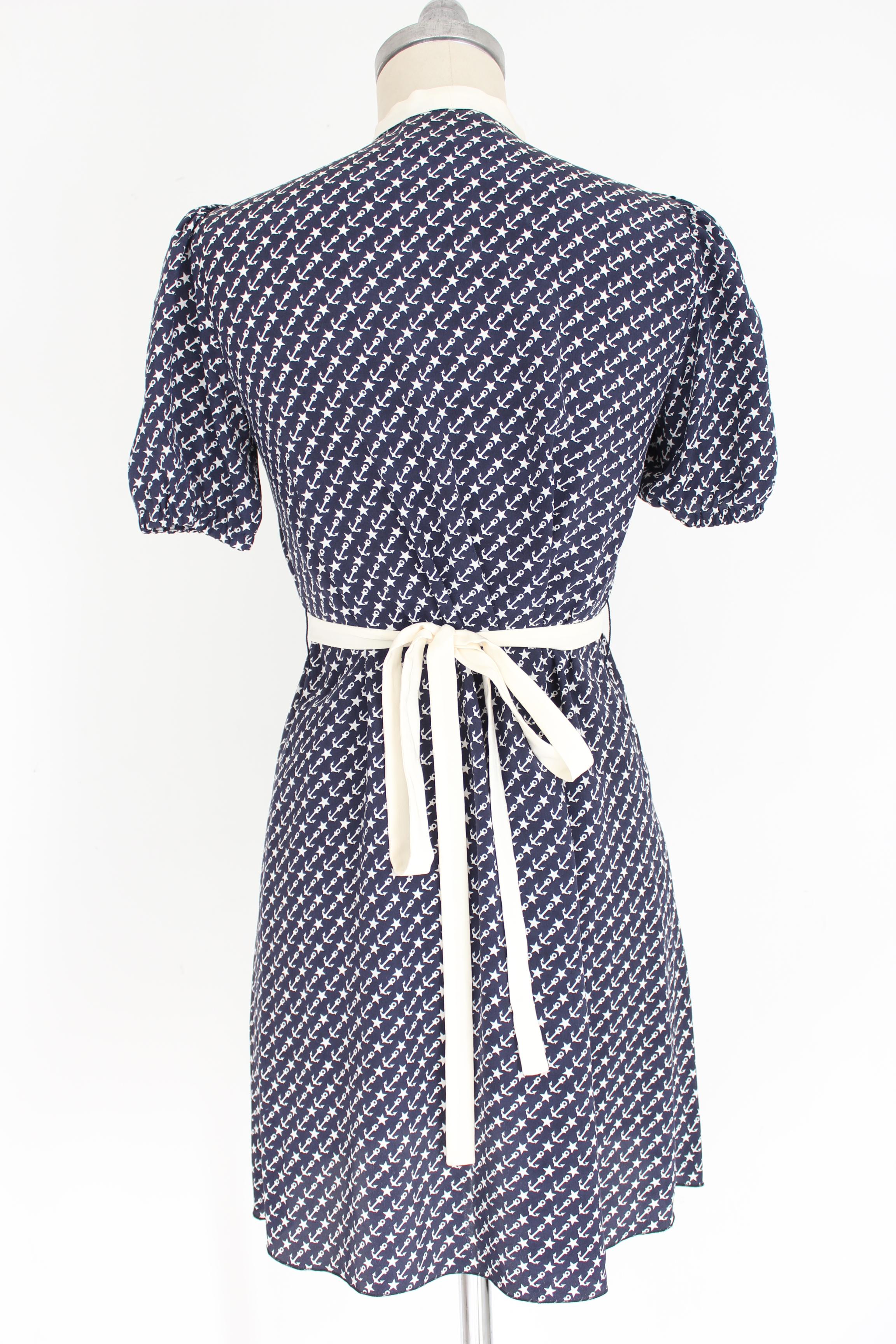 Dolce & Gabbana 90s vintage woman dress. Short dress on the knee, blue and beige with anchor and star designs. Closure with bow at the neck and deep neckline on the decollete. Adjustable waist belt. 100% silk. Made in Italy. Excellent vintage