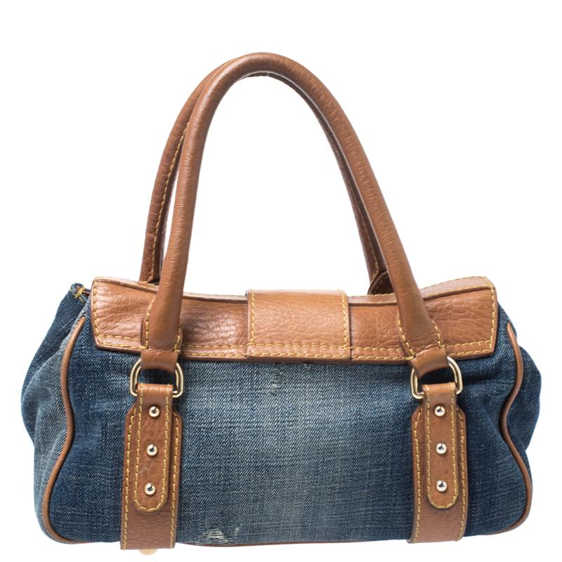 This opulent and chic D-ring satchel coming from Dolce & Gabbana is a must-have. It is crafted from denim fabric and leather, featuring two rolled handles and a flap closure. This bag comes with fabric-lined interior which houses a zipped pocket