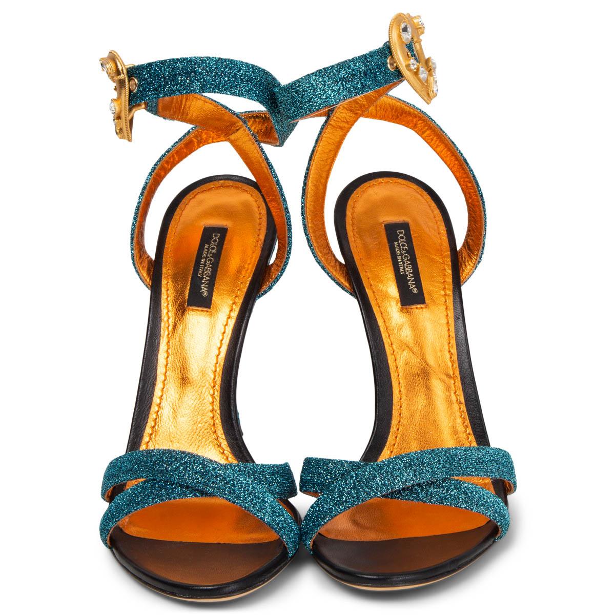 100% authentic Dolce & Gabbana sandals in turquoise metallic soft lurex fabric. The design features crisscrossing bands at the toe and a slim ankle strap with a golden crystal-embellished metal heart. Have bee worn once inside and are in virtually