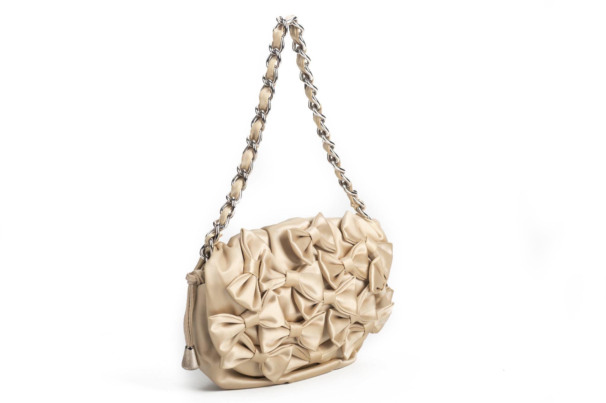 Dolce & Gabbana evening bag made of silk in cream white. The bag is decorated with multiple small bows on the front. It comes with a shoulder chain and it opens with a zip on top of it. The piece is in excellent condition and comes with a dustcover.