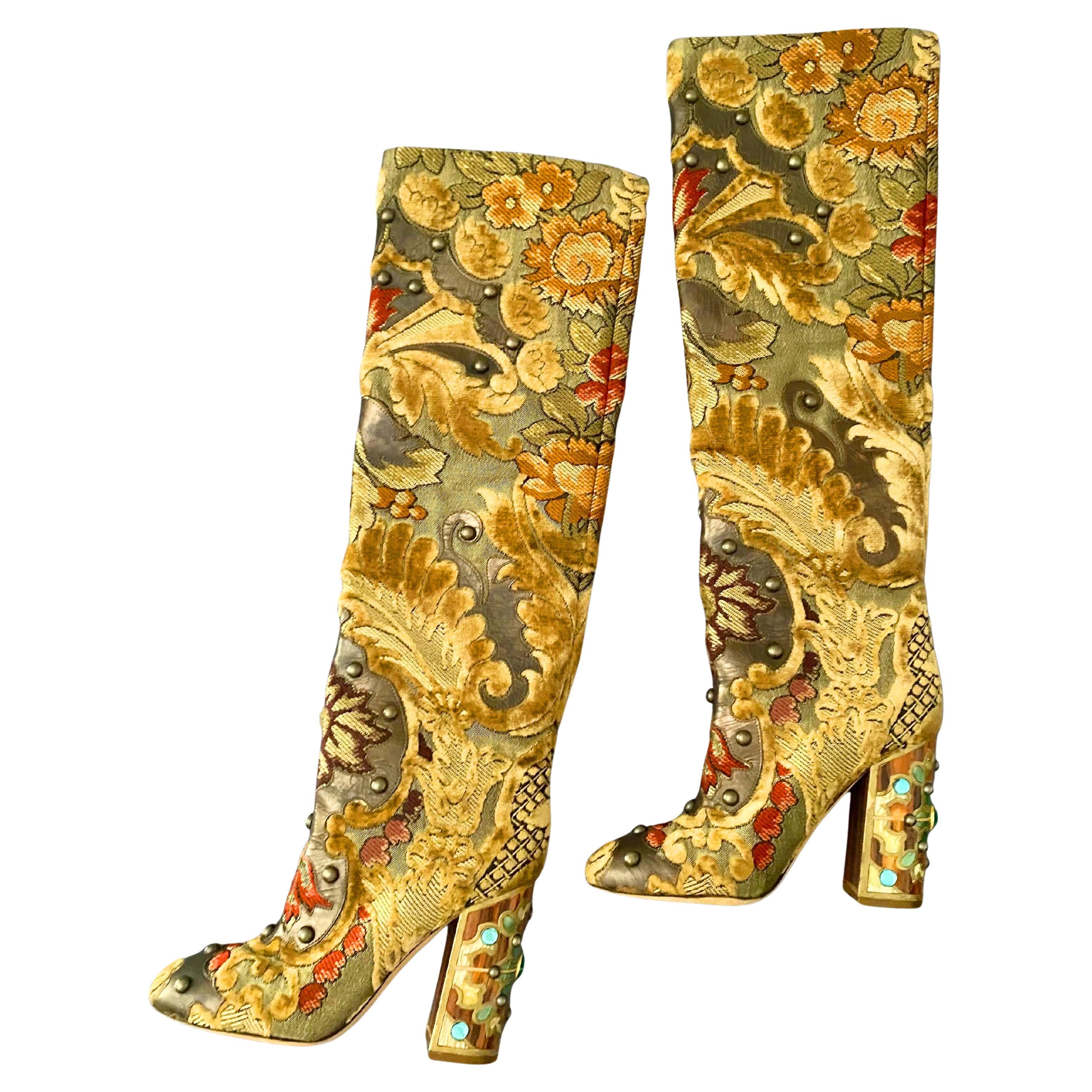 Die Over-the-Knee-Stiefel von Dolce & Gabbana aus mehrfarbigem Brokatstoff bestechen durch die Kombination aus beigem Samt, braunem Leder und aufwendigen Verzierungen wie Steinen und Nieten. Der Absatz ist mit handwerklichen Holzdetails verziert,