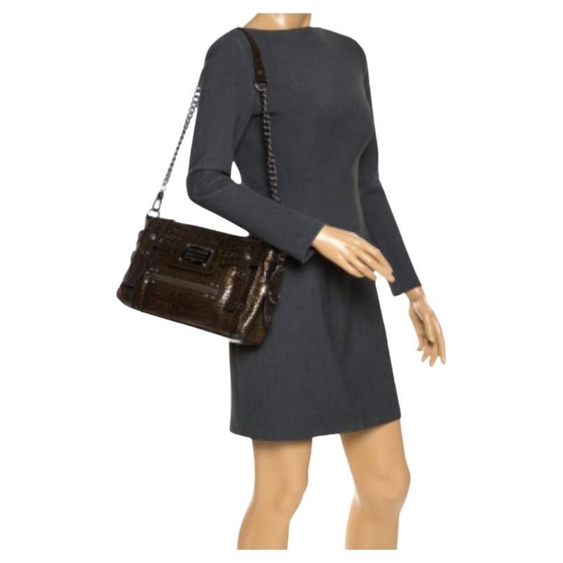 Questa elegante borsa Miss Easy Way di Dolce & Gabbana valorizzerà il tuo abbigliamento casual e da sera. Realizzata in vernice goffrata croc in colore marrone, è decorata con la targhetta del marchio e una tasca con zip sul davanti. La borsa è