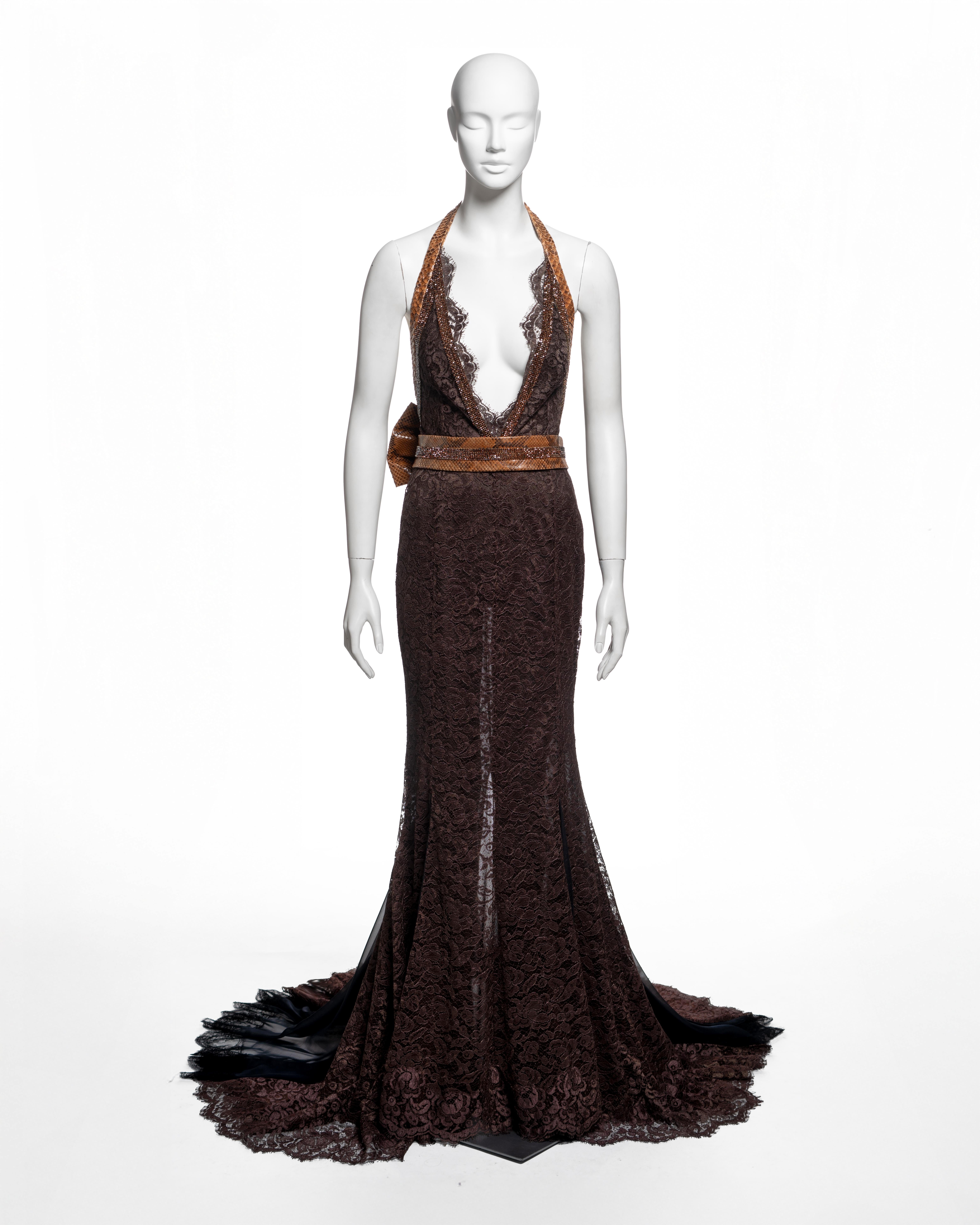 Dolce & Gabbana, primavera-estate 2005. Abito lungo fino al pavimento in pizzo floreale marrone, tagliato a colonna con orlo svasato e inserti in chiffon nero che formano uno strascico corto. Profonda scollatura a V fino alla vita, bordi rifiniti