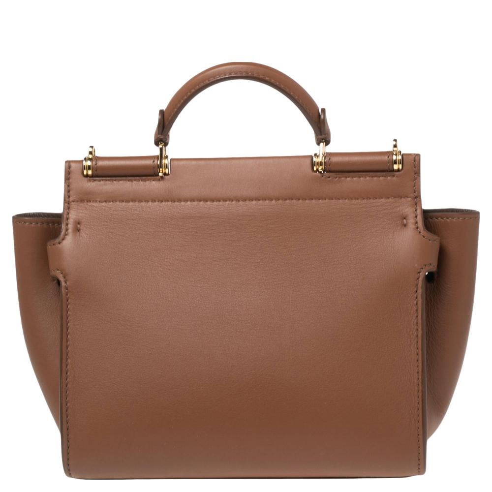 Meticulously crafted into an eye-catchy shape, this Sicily 62 tote from the House of Dolce & Gabbana exudes just the right amount of charm and elegance! It is made from brown leather with a logo detail accentuating the front. It has gold-toned