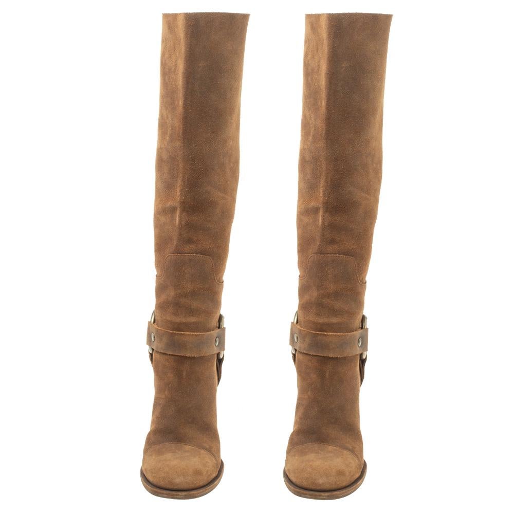 Dolce & Gabbana brings you this fabulous pair of knee-high boots that will give you confidence and loads of style. They've been crafted from suede in a lovely brown shade and styled with round toes, strap details and 7 cm wedge heels.
