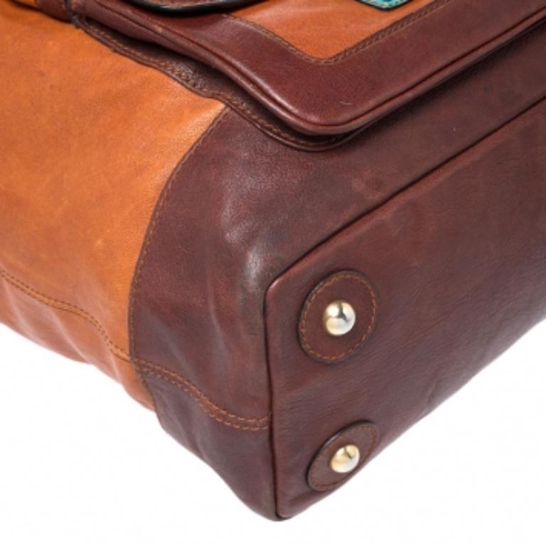 This excellent Dolce and Gabbana bag exudes brilliance and outstanding craftsmanship. Crafted from brown leather, it is enhanced with turquoise leather trims and flaunts dual pockets on the front. The interior is fabric lined and the bag can be held
