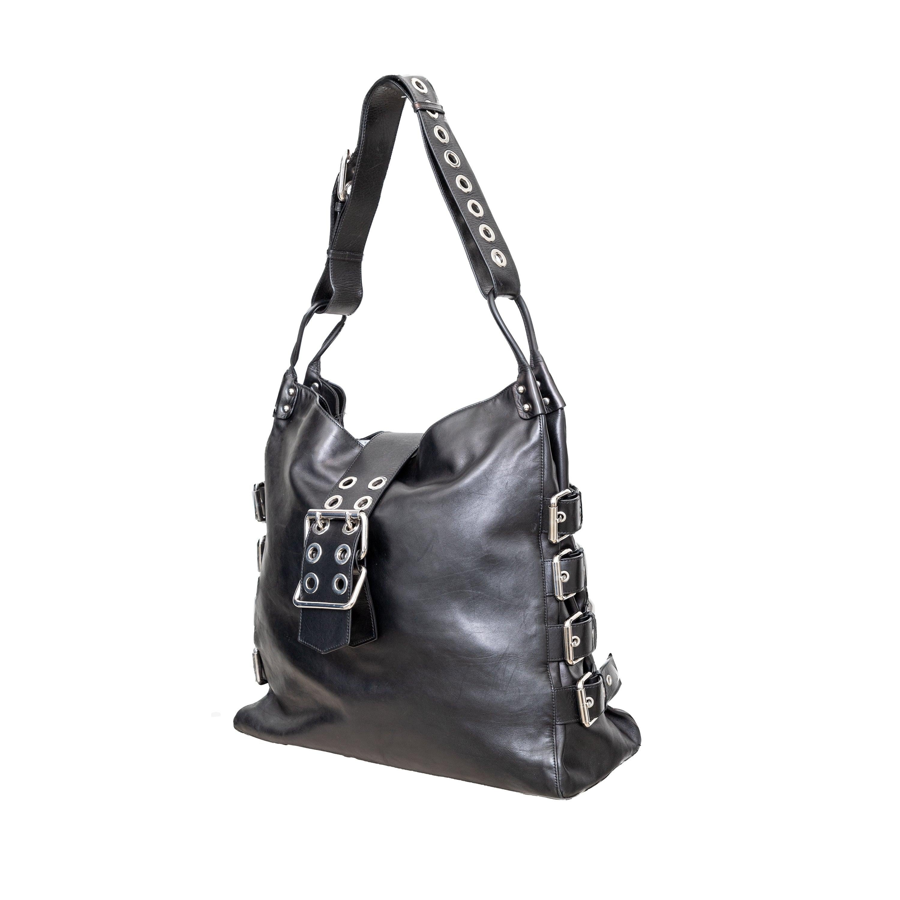 This black leather shoulder bag from Dolce & Gabbana's Spring 2003 Sex Collection features sleek straps and buckles on the sides for a bold and edgy look. Its hobo bag shape and adjustable shoulder strap offer both style and practicality. With two