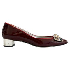 Dolce & Gabbana Pumps aus burgunderrotem Lackleder mit niedrigem Absatz und silbernen Metallbeschlägen