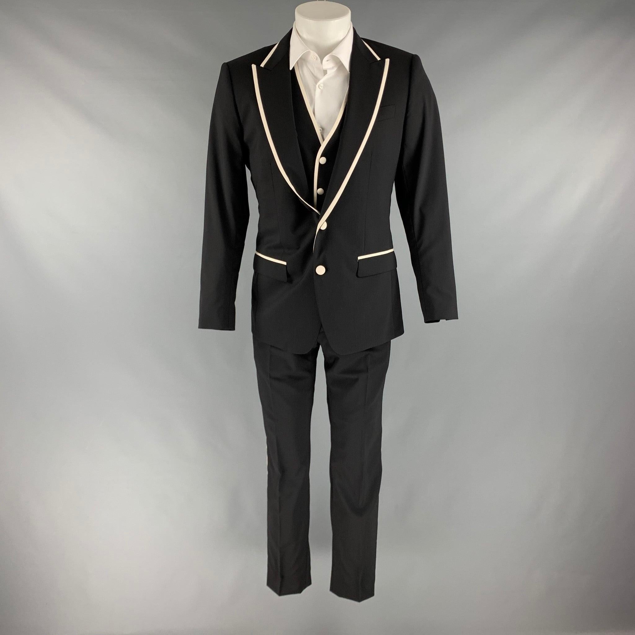 DOLCE & GABBANA
suit in a black wool blend with white trim, featuring
 a full liner and includes a single breasted, double button sport coat with peak lapel and matching flat front trousers. Made in Italy.Very Good Pre-Owned Condition. 

Marked:  