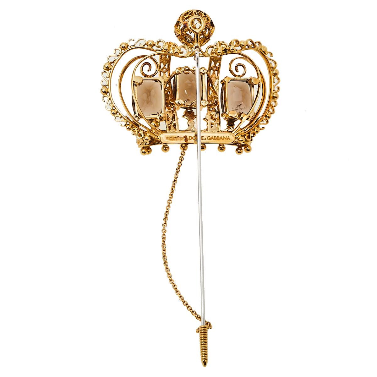 Dolce & Gabbana's collections are a testament to the label's opulent and glamorous aesthetics. This pin brooch is sculpted from 18K yellow gold into a crown motif, a symbol that is often seen on the label's collection. It is detailed with diamonds