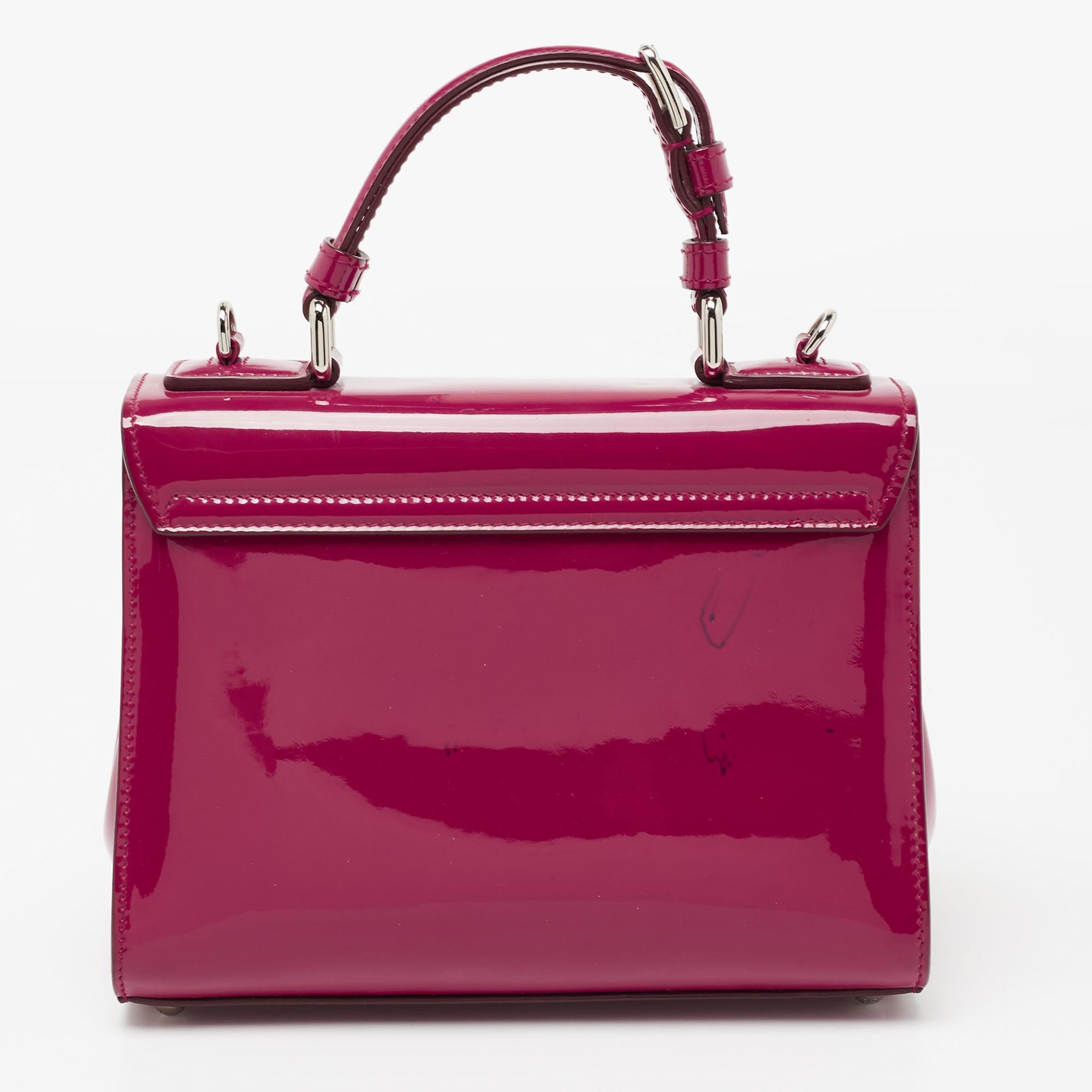 Well-structured and high on style, this Miss Monica bag from Dolce & Gabbana deserves to be yours! It is crafted from patent leather and styled with a top handle and an optional shoulder strap. It also comes with a silver-tone latch lock on the