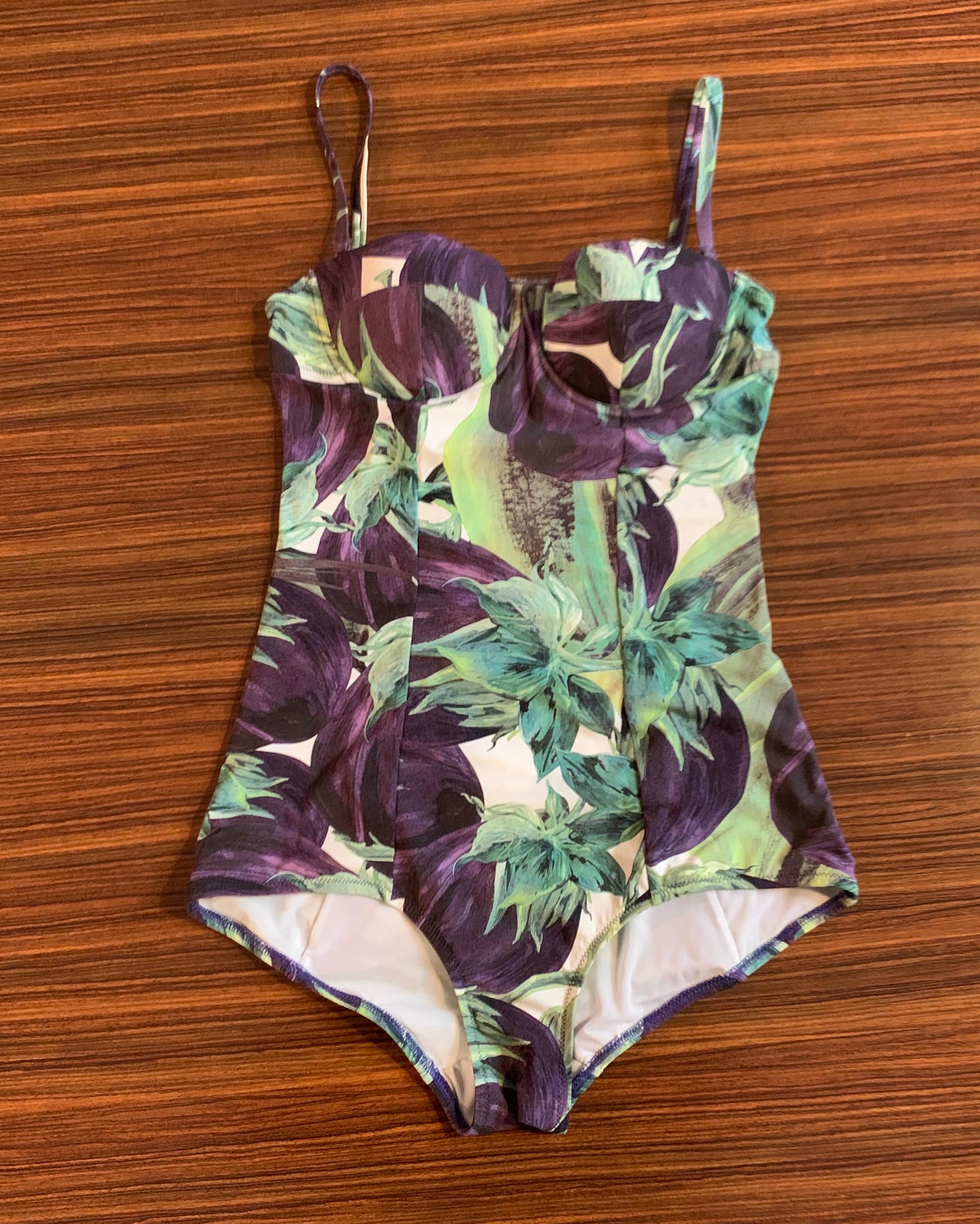 Dolce & Gabbana eggplant print one piece swimming suit. Low cut back with cross strap featuring silver clasp branded 'Dolce & Gabbana' Padded cups with underwire provide support & boost. Can be worn with or without detachable straps.

72% nylon, 28%