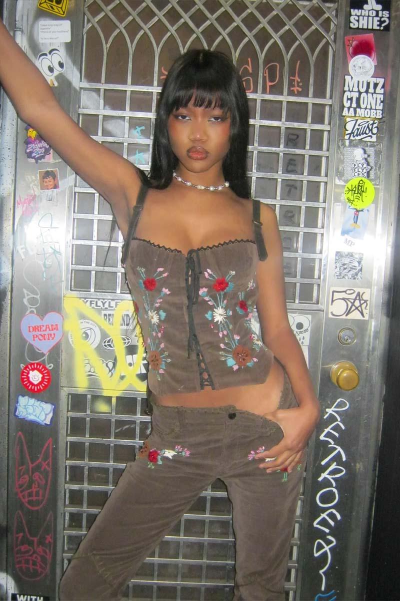 Dolce & Gabbana Autunno-Inverno 2002: set ricamato in velluto a coste. Il top è caratterizzato da un corpo in velluto a coste con spalline regolabili in pelle scamosciata, silhouette bustier, allacciatura sul davanti e sul retro e fiori ricamati con