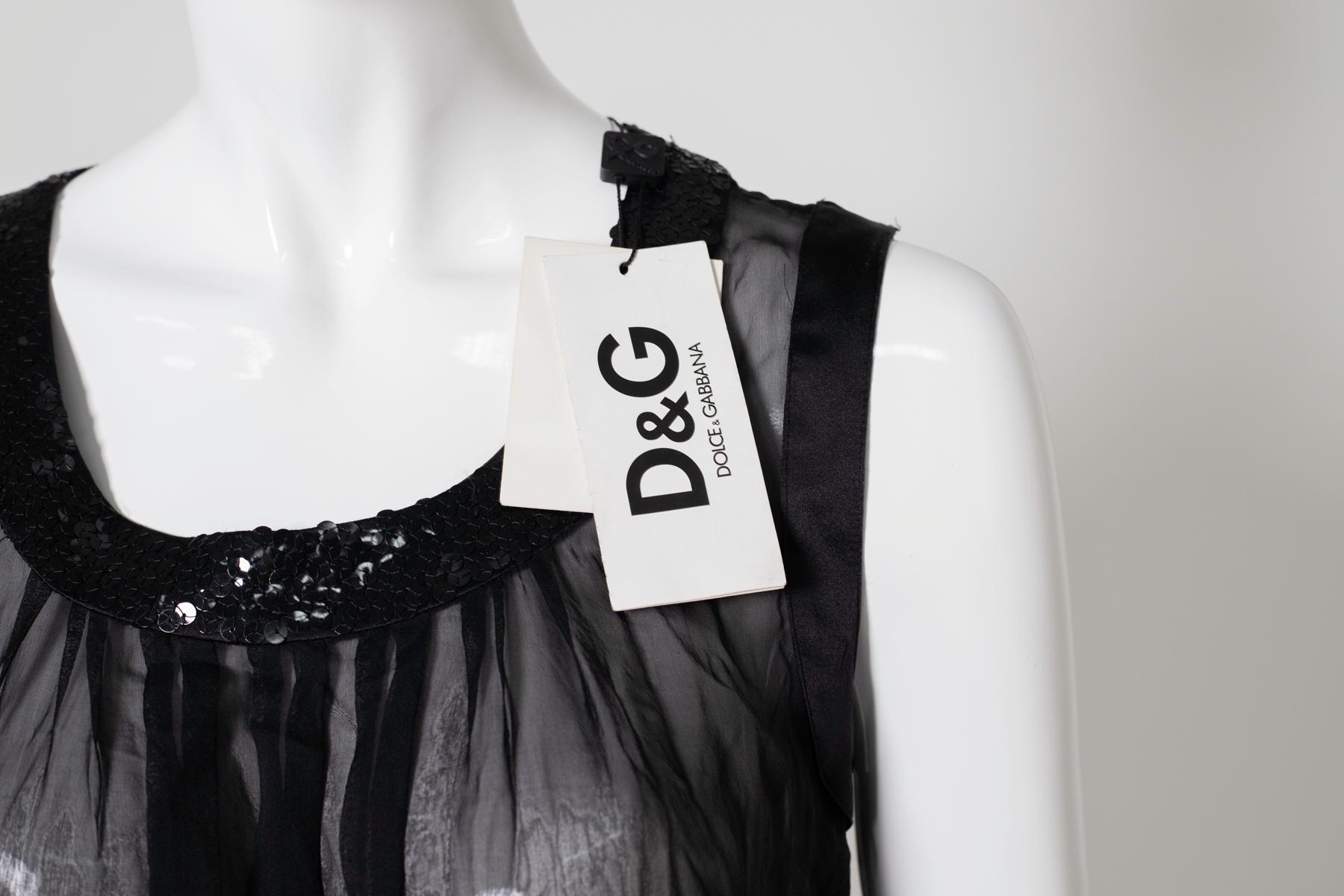 Dolce & Gabbana  Cocktail dress.  Black illusion mesh on the front and back of the bodice. Never used with label. Drop-shaped back. Spoon neckline with paillettes. Keyhole on the back with two button and loop fastenings and silk satin ties at
