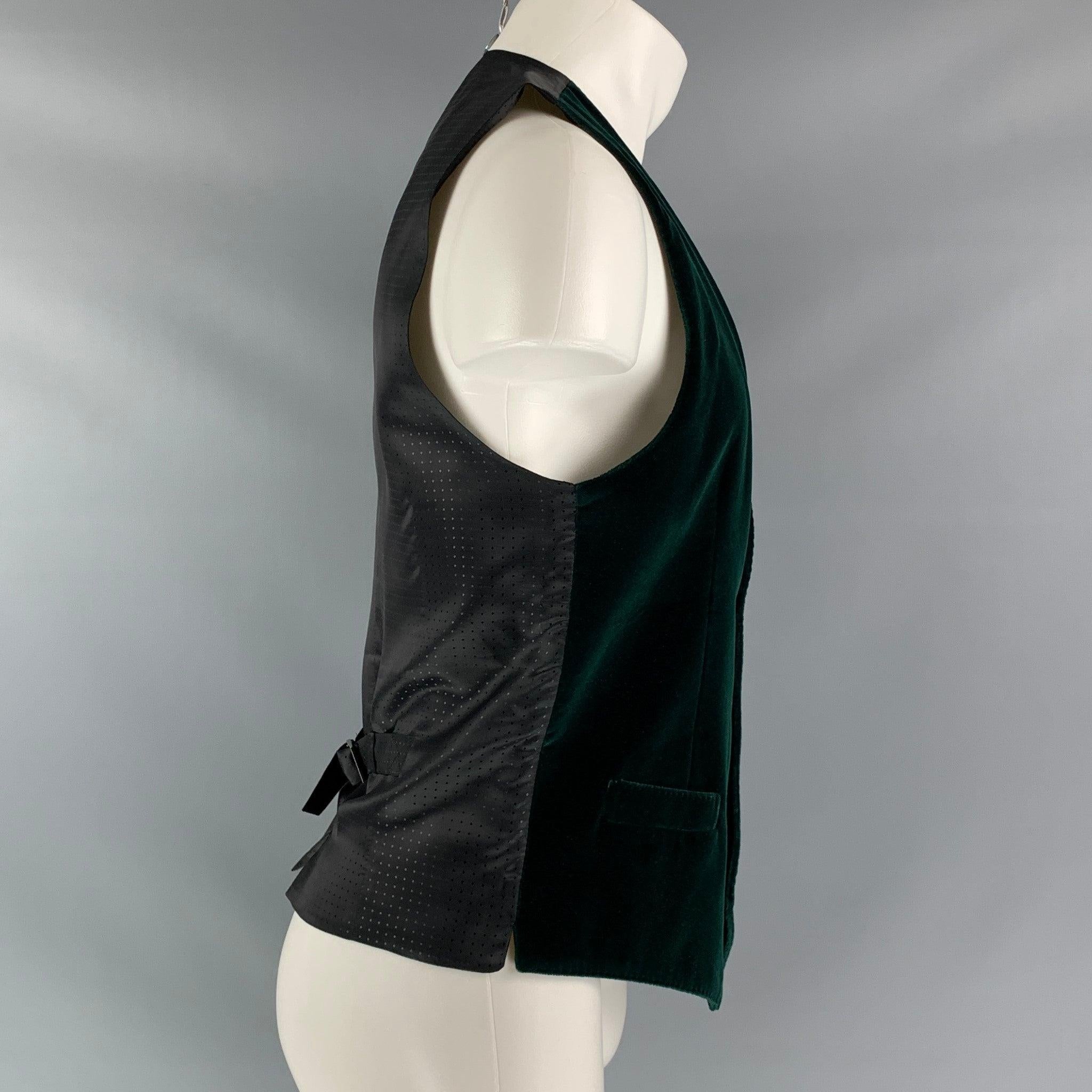 DOLCE & GABBANA dress vest comes in a green esmerald velvet fabric, full lined featuring V-neck, welt pockets, four buttons down closure, black viscose fabric back and adjustable belt. Made in Italy.Excellent Pre-Owned Condition.  
 

 Marked:  48