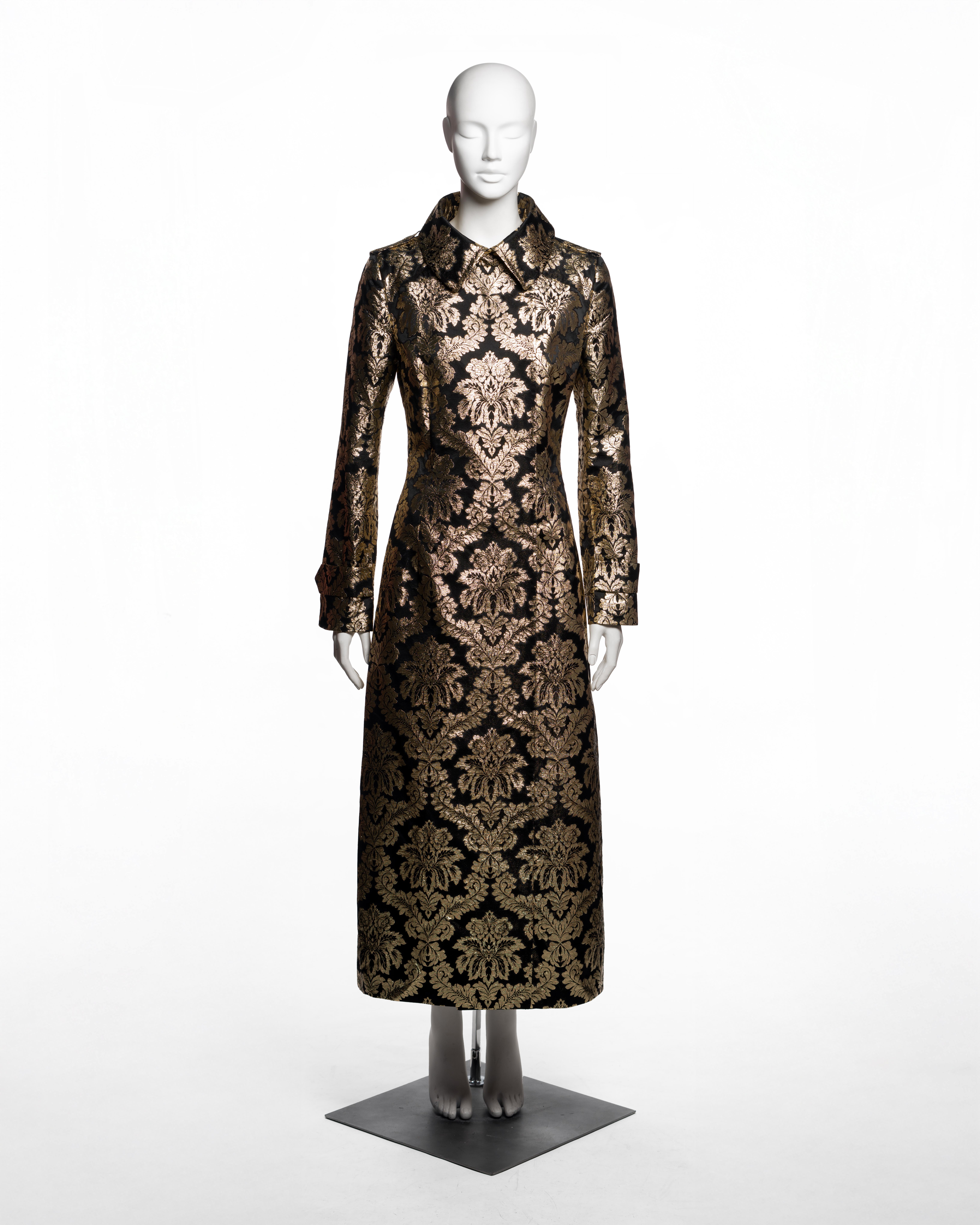 This Dolce & Gabbana coat from the Fall-Winter 2000 collection is tailored in black silk brocade woven with a large-scale metallic gold floral motif, evoking Baroque textile traditions. Cut to a three-quarter length, the garment features a sharply