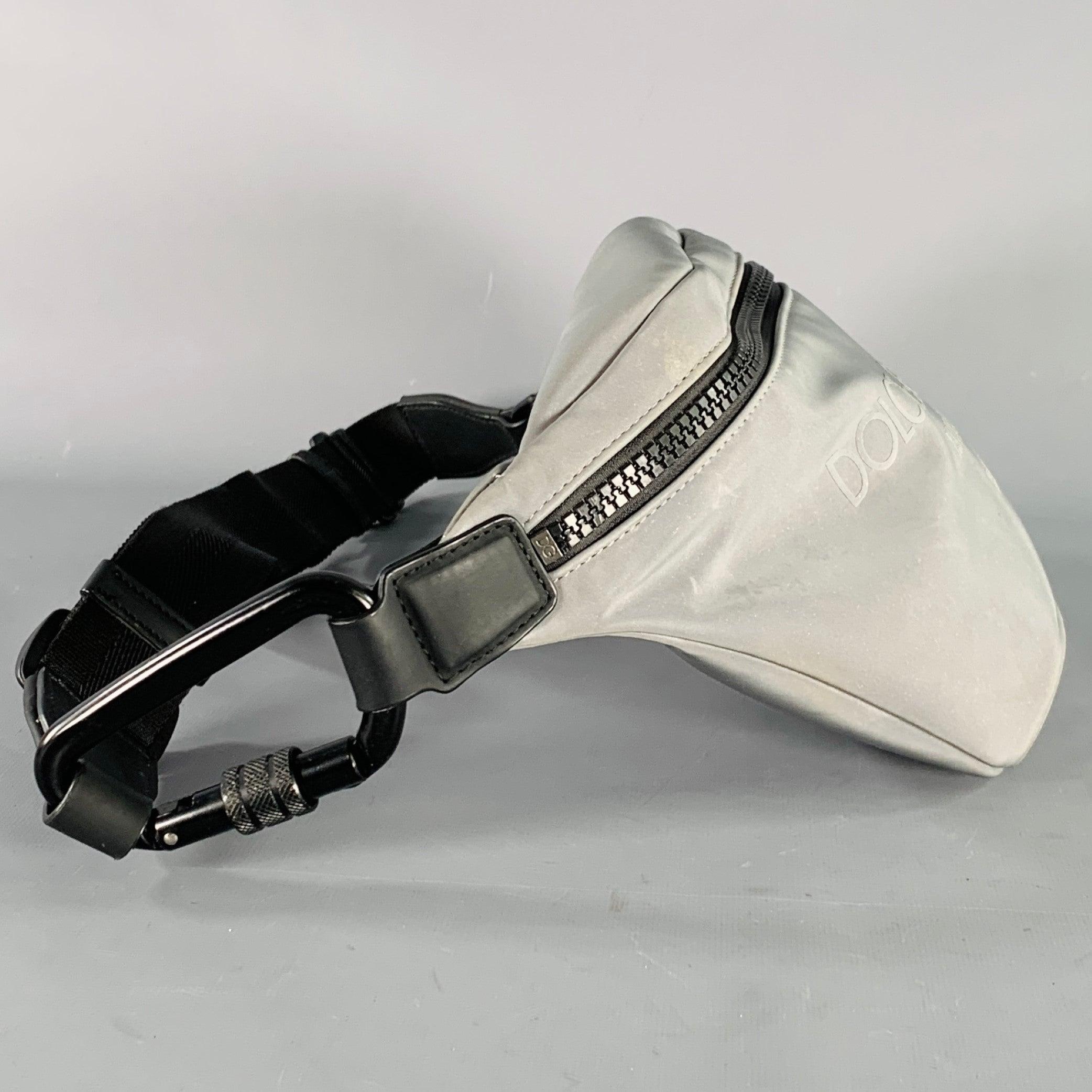 DOLCE & GABBANA belt bag
in a reflective metallic grey canvas featuring an adjustable fit, tonal logo, and zip closure. Made in Italy.Good Pre-Owned Condition.
Multiple minor marks. 

Measurements: 
  Length: 11.5 inches Width: 2 inches Height: 6