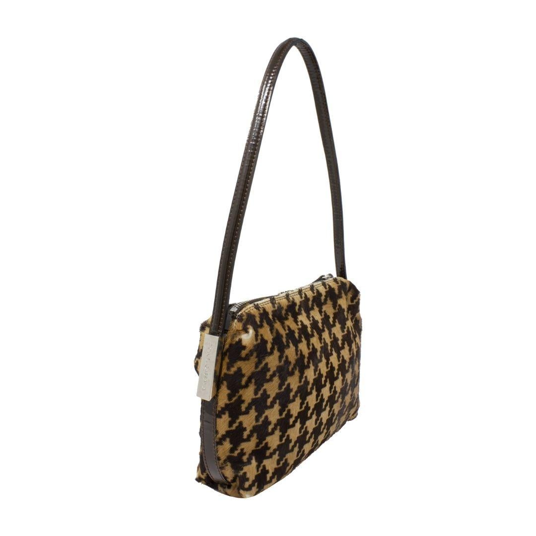 Super cute Dolce & Gabbana houndstooth baguette with silvertone hardware and a zip top closure. We love the patent black leather strap and the Dolce & Gabbana logo placards on each side. The zip top closure opens up to a black satin