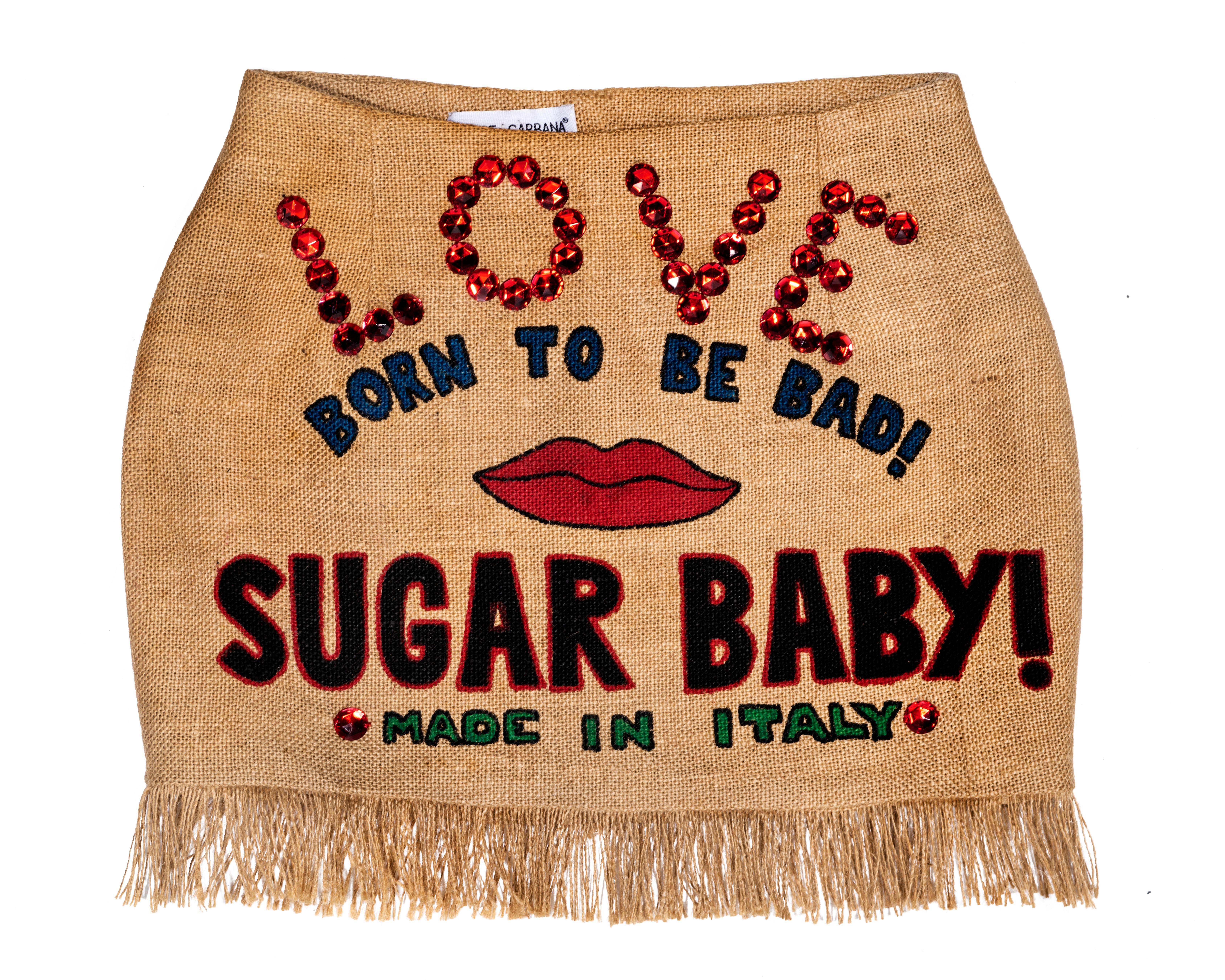 ▪ Iconic Dolce & Gabbana jute mini skirt 
▪ Hand painted designs ('BORN TO BE BAD!', red lips, 'SUGAR BABY!', and 'MADE IN ITALY')
▪ Large red gems ('LOVE')
▪ Fringe hemline 
▪ W 27
