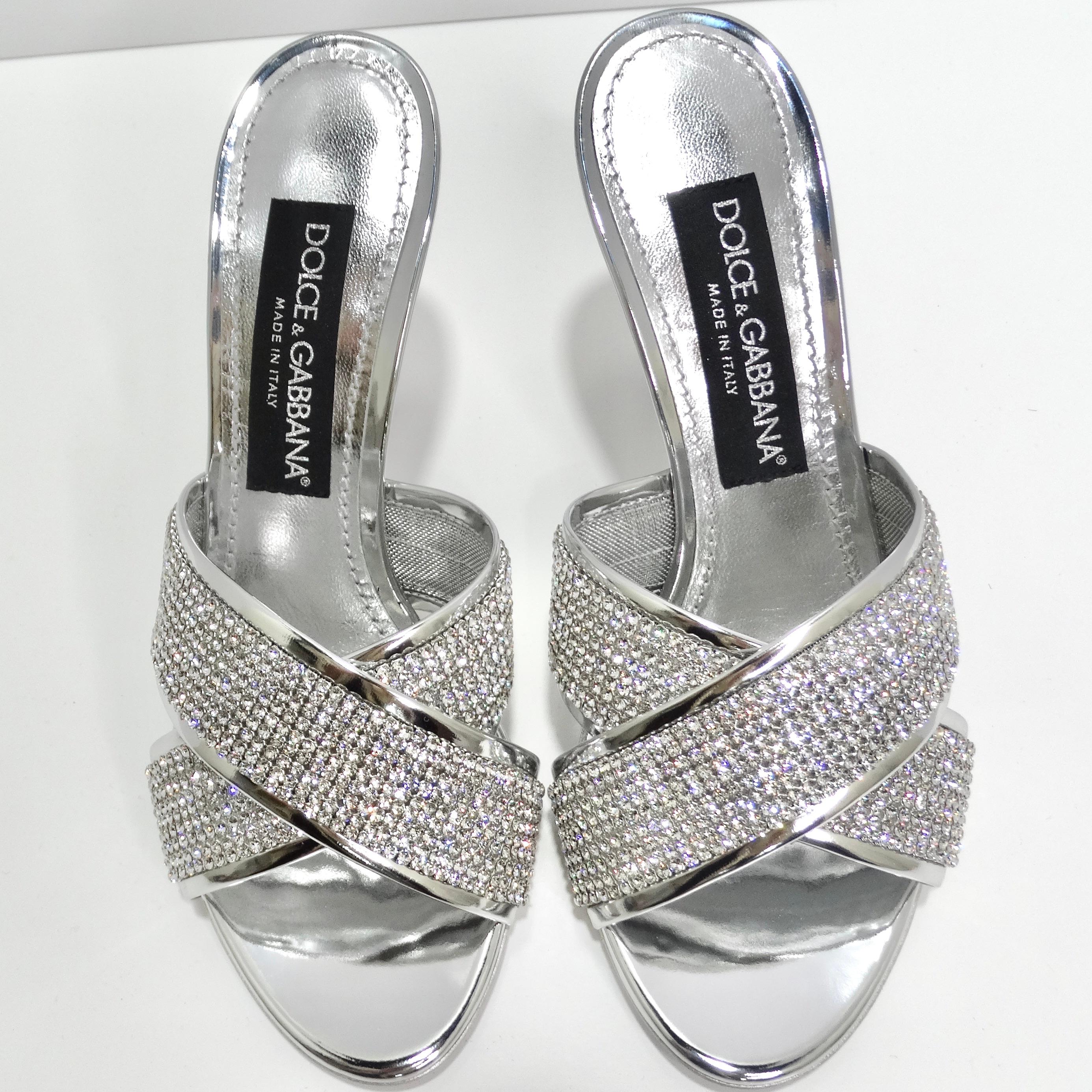 Step into the spotlight with the Dolce & Gabbana Keira Crystal-Embellished Mules – a pair of metallic silver leather heels that redefine glamour. The mule-style design brings a touch of sophistication, while the crystal-embellished mesh straps add a