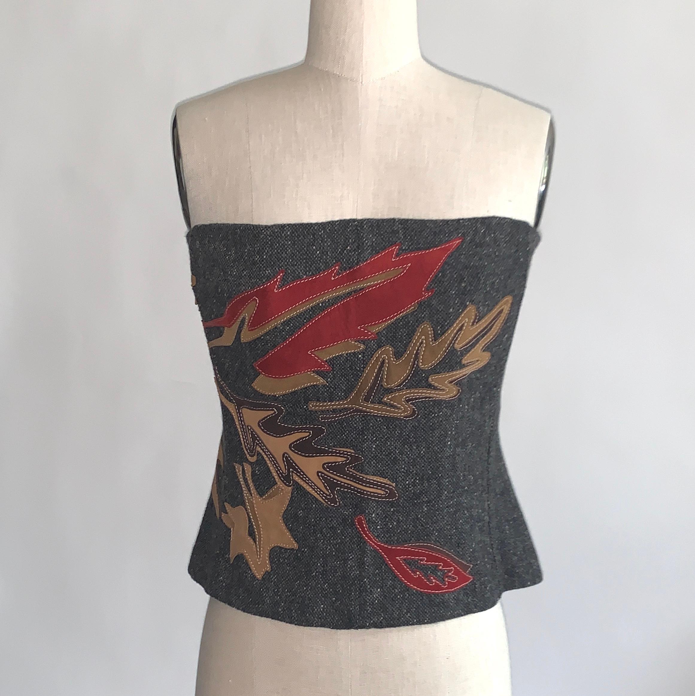 Dolce & Gabbana grey tweed strapless corset top in grey tweed with red and brown leather suede leaf appliqué at front and side. Boning at interior for shape and structure. Back zip and hook and eye. 

80% lambswool, 20% leather.
Fully lined in 56%