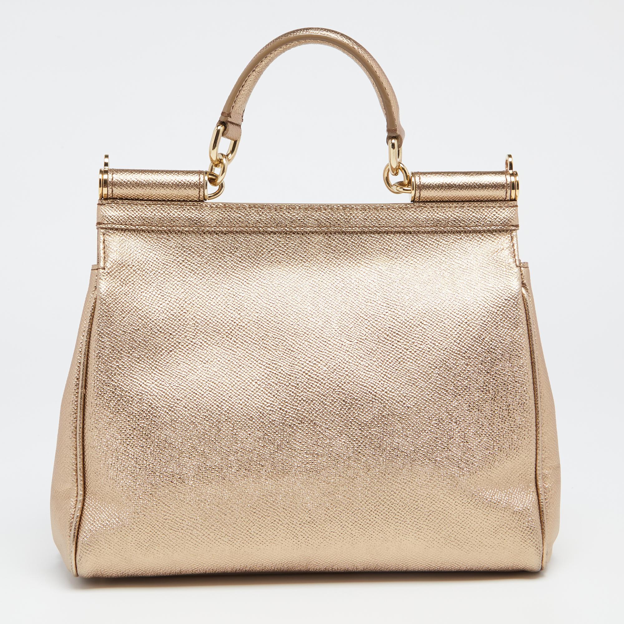 Meticulously crafted into an eye-catchy shape, this Miss Sicily bag from the House of Dolce & Gabbana exudes just the right amount of charm and elegance! It is made from metallic-gold leather, with a gold-toned logo plaque accentuating the front. It