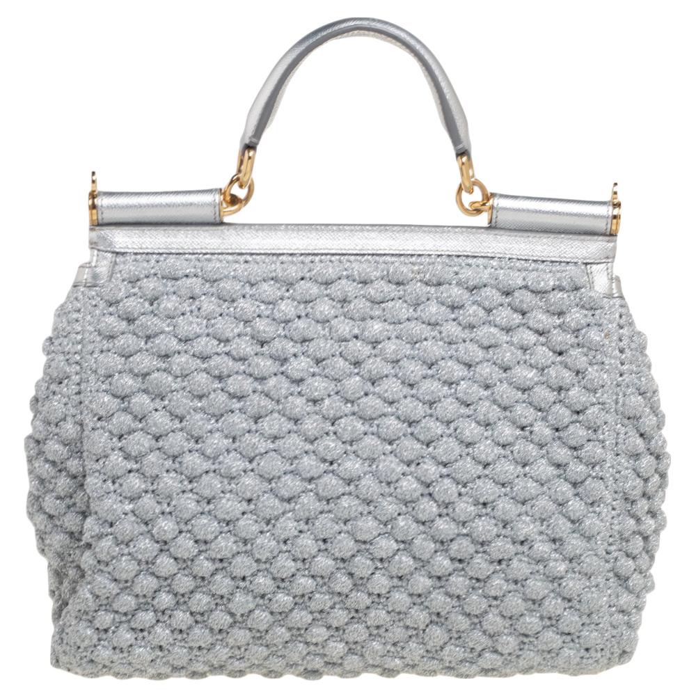 The iconic Miss Sicily bag by Dolce & Gabbana is named after Domenico Dolce's native land and exhibits the aesthetic of Italian glamour. The neat silhouette is made from leather & crochet in metallic silver and features a front flap accented with